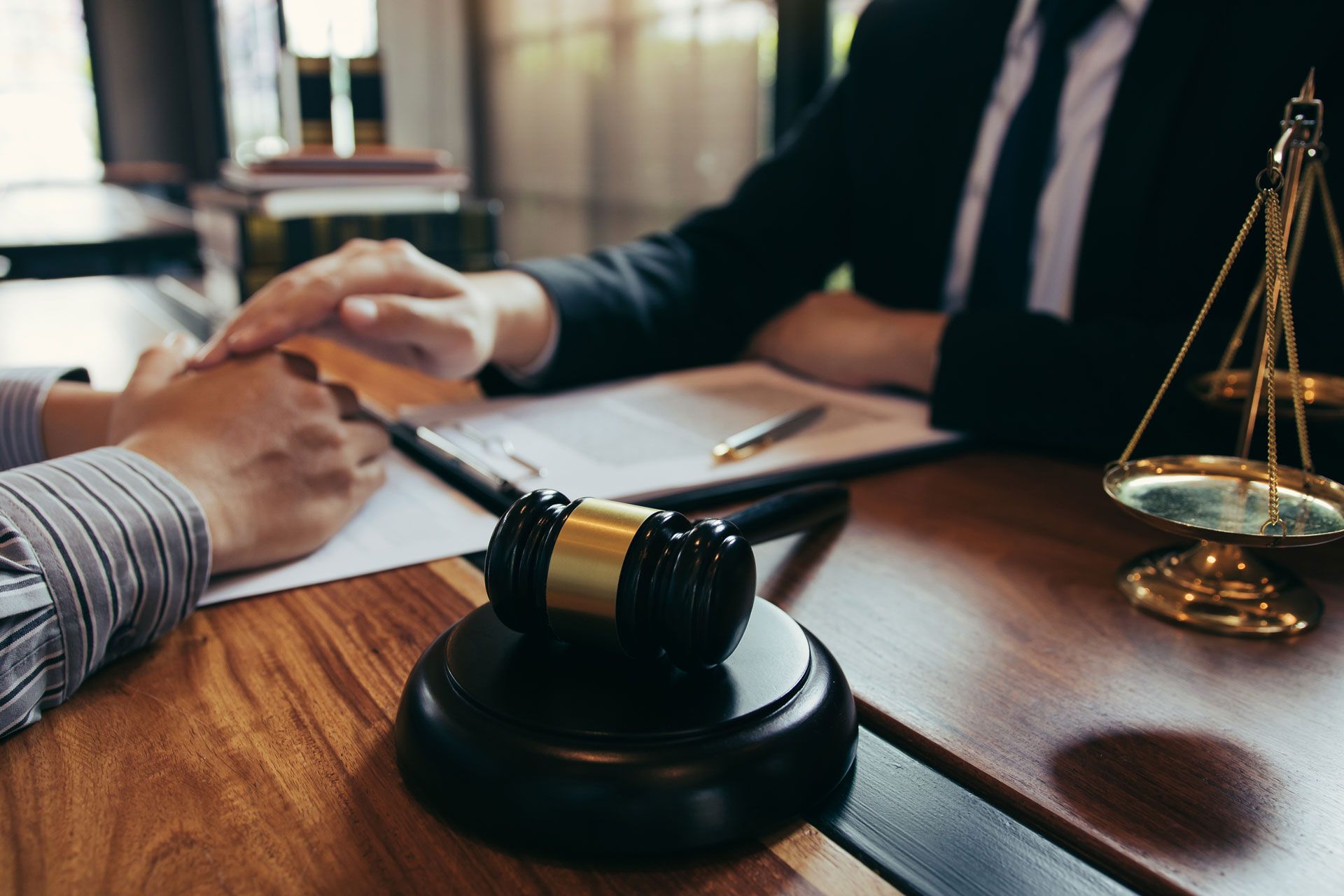 A man is sitting at a table with a judge's gavel and a scale of justice