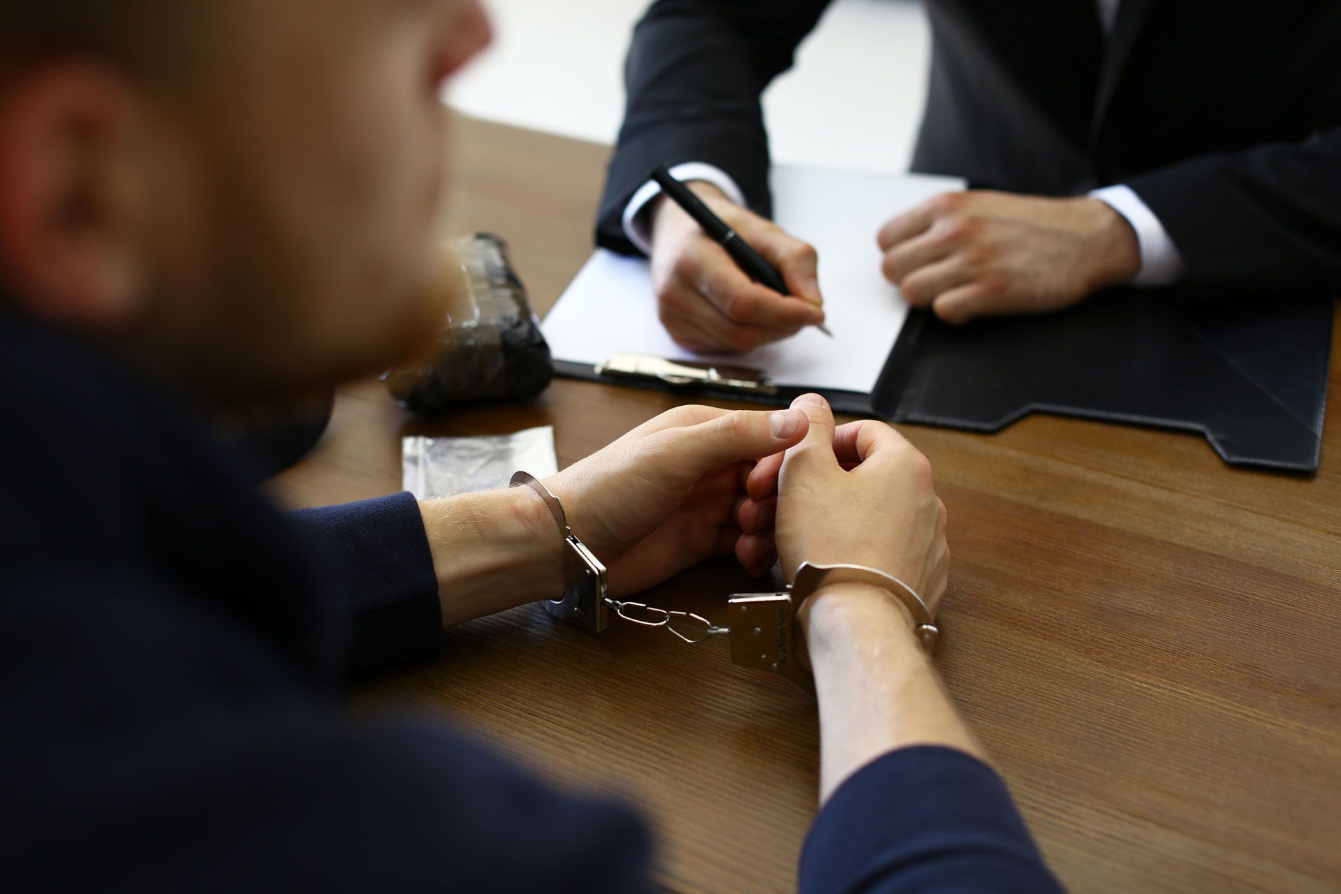 A man in handcuffs is sitting at a table talking to a lawyer