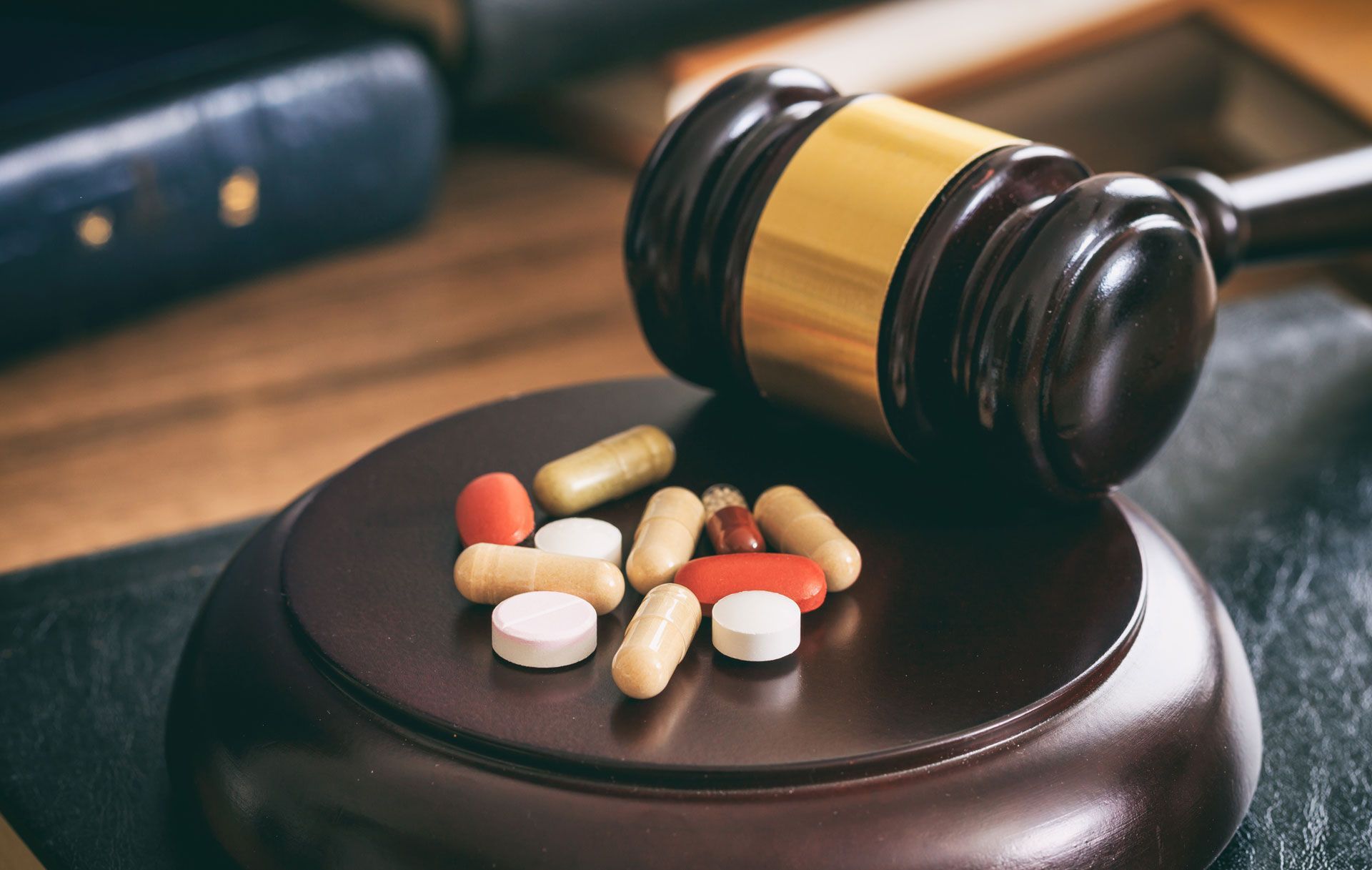 A judge 's gavel is sitting on top of a wooden block with pills on it