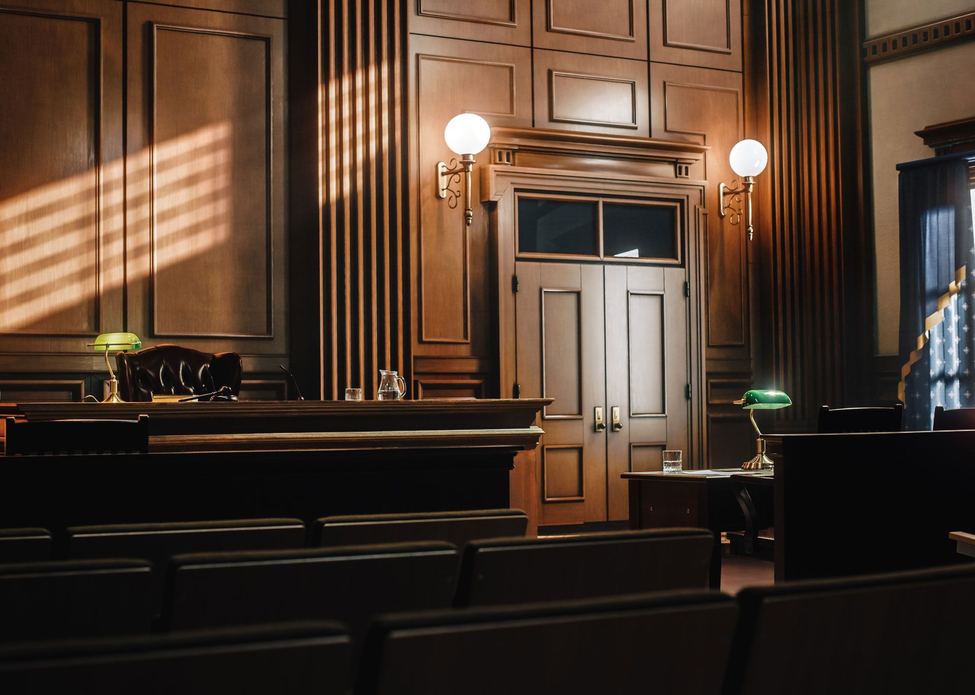 An empty courtroom with wood paneling and a green lamp