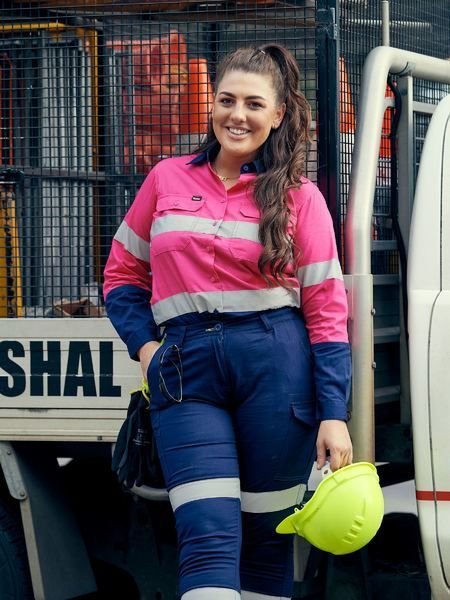 A Woman in a Pink Shirt and Blue Pants is Holding a Yellow Hard Hat — Hi-Vis Workwear in Townsville