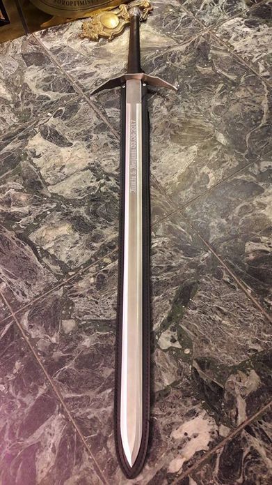 Ein graviertes Schwert liegt auf Steinboden.