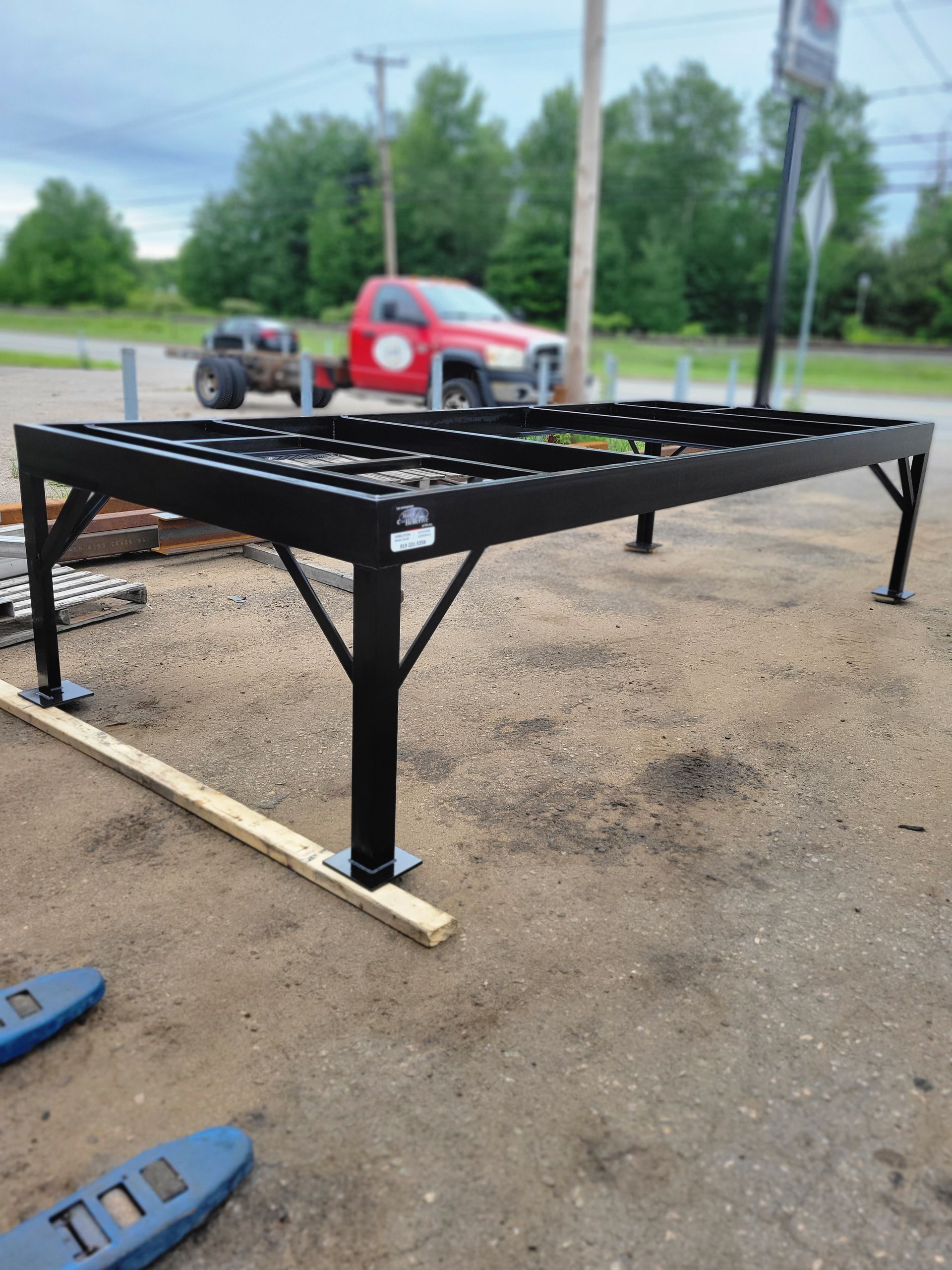 Une plate-forme métallique est posée sur le sol devant un camion rouge.