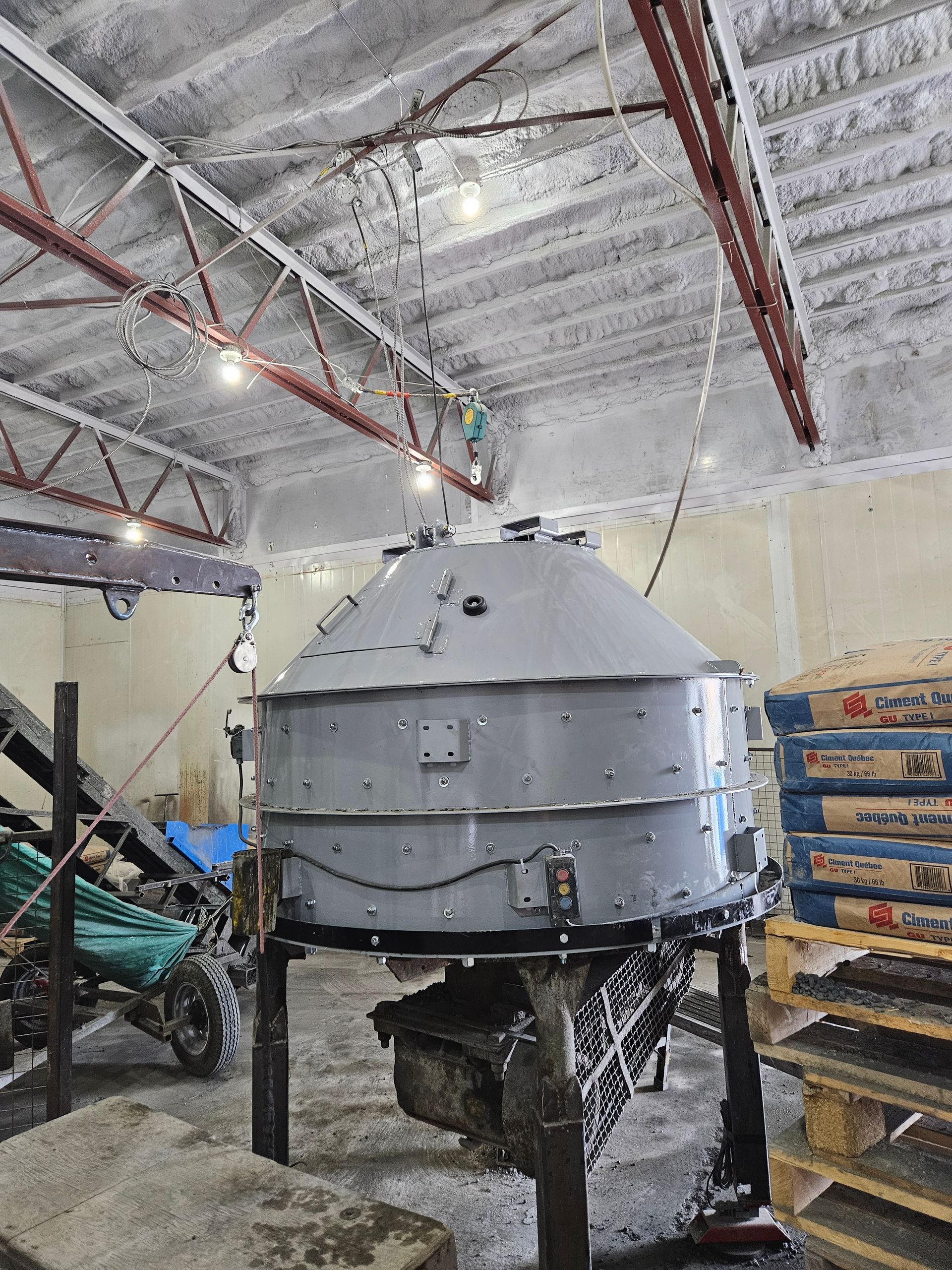Une grande machine est assise dans un entrepôt à côté d'une pile de palettes.