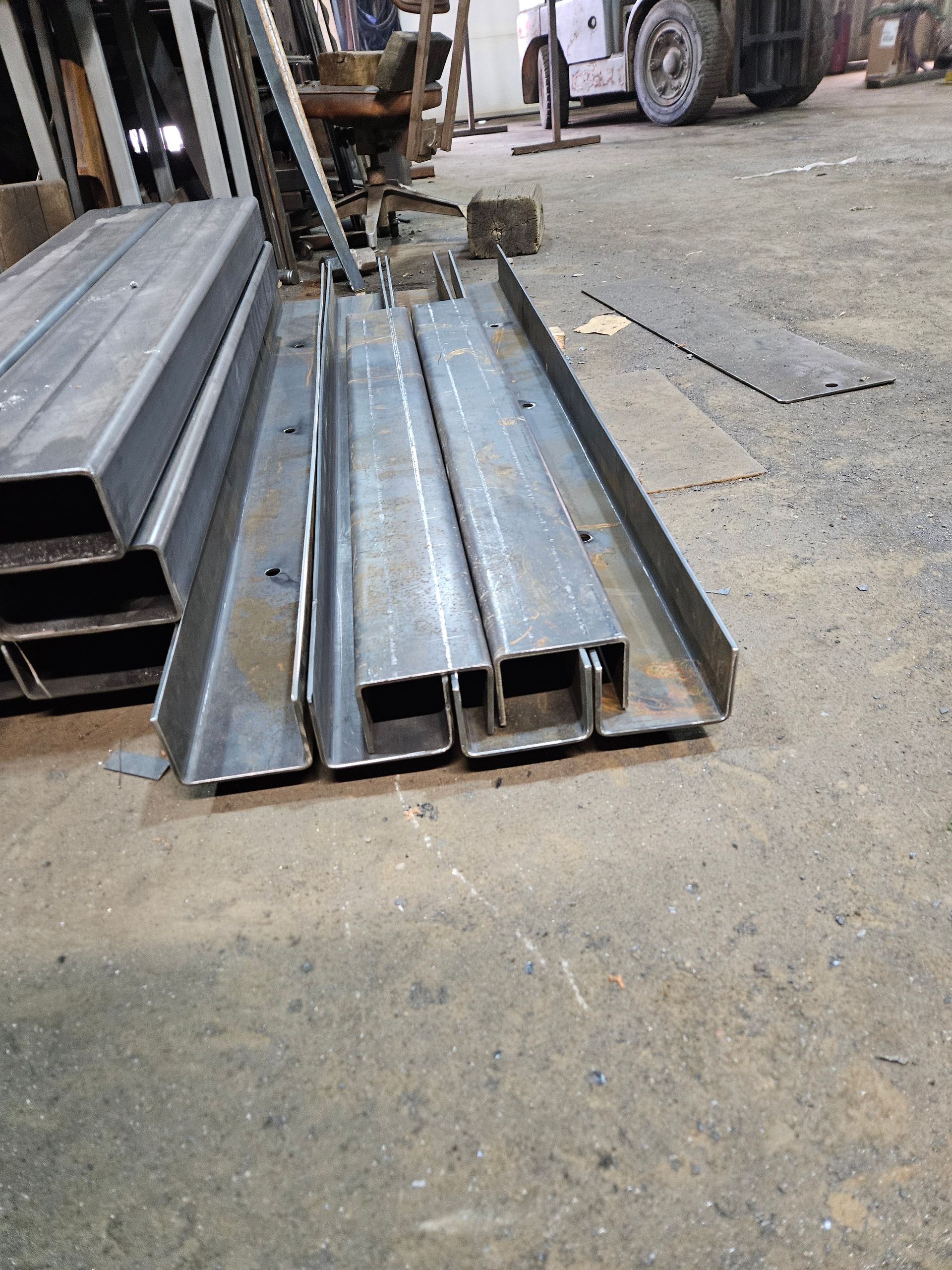 Un tas de tuyaux métalliques sont posés sur le sol dans une usine.