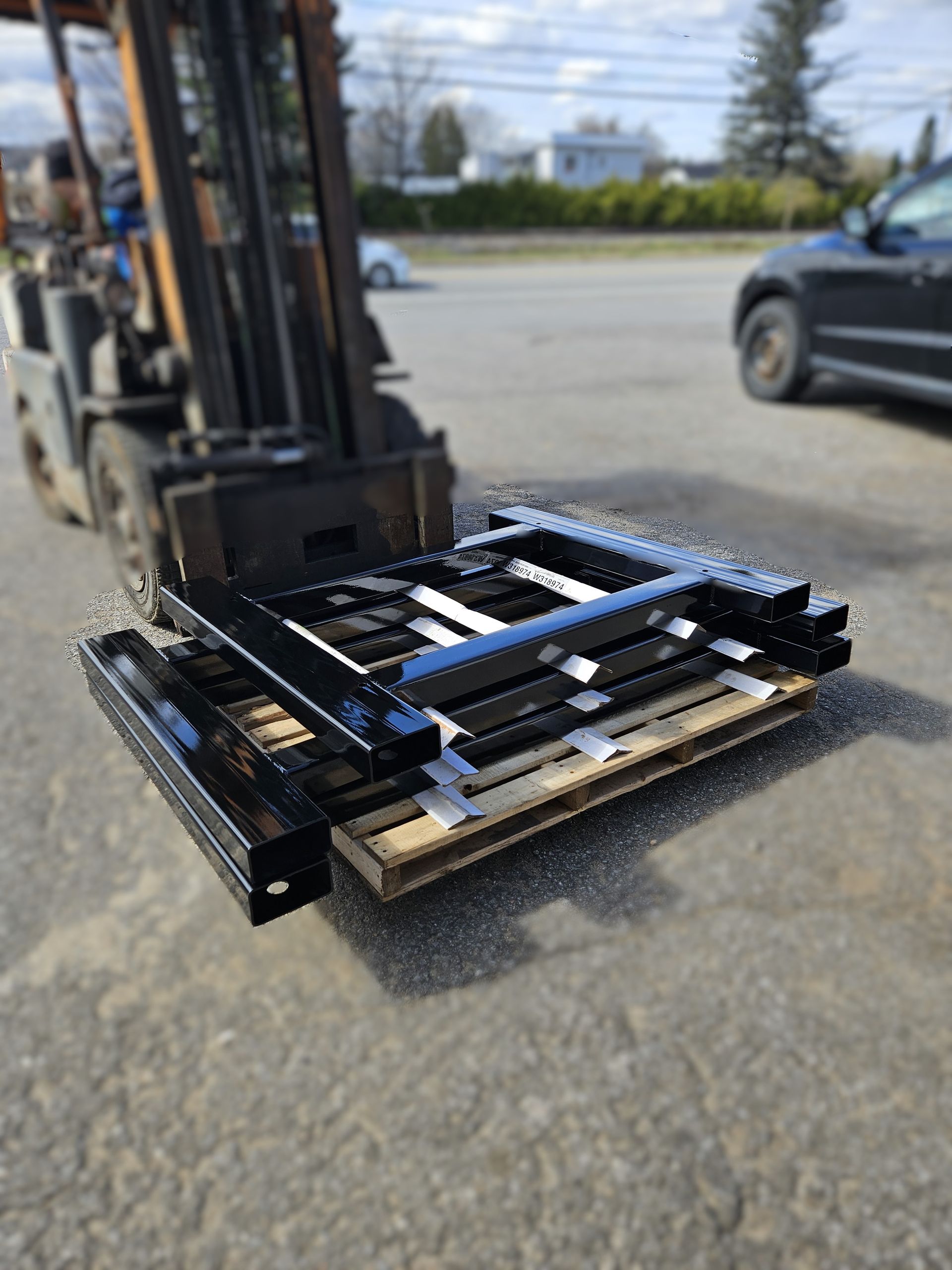 Un chariot élévateur transporte une pile de pièces métalliques sur une palette en bois.