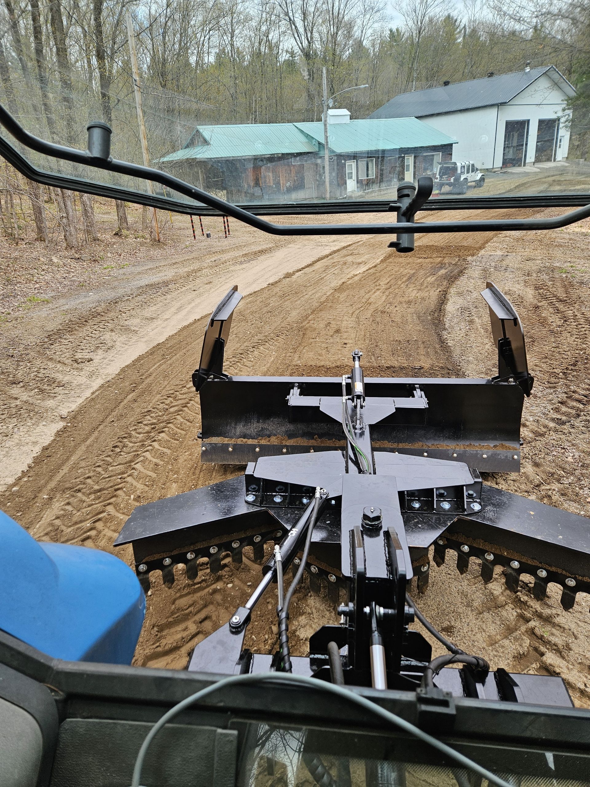 Une personne conduit un tracteur sur un chemin de terre.