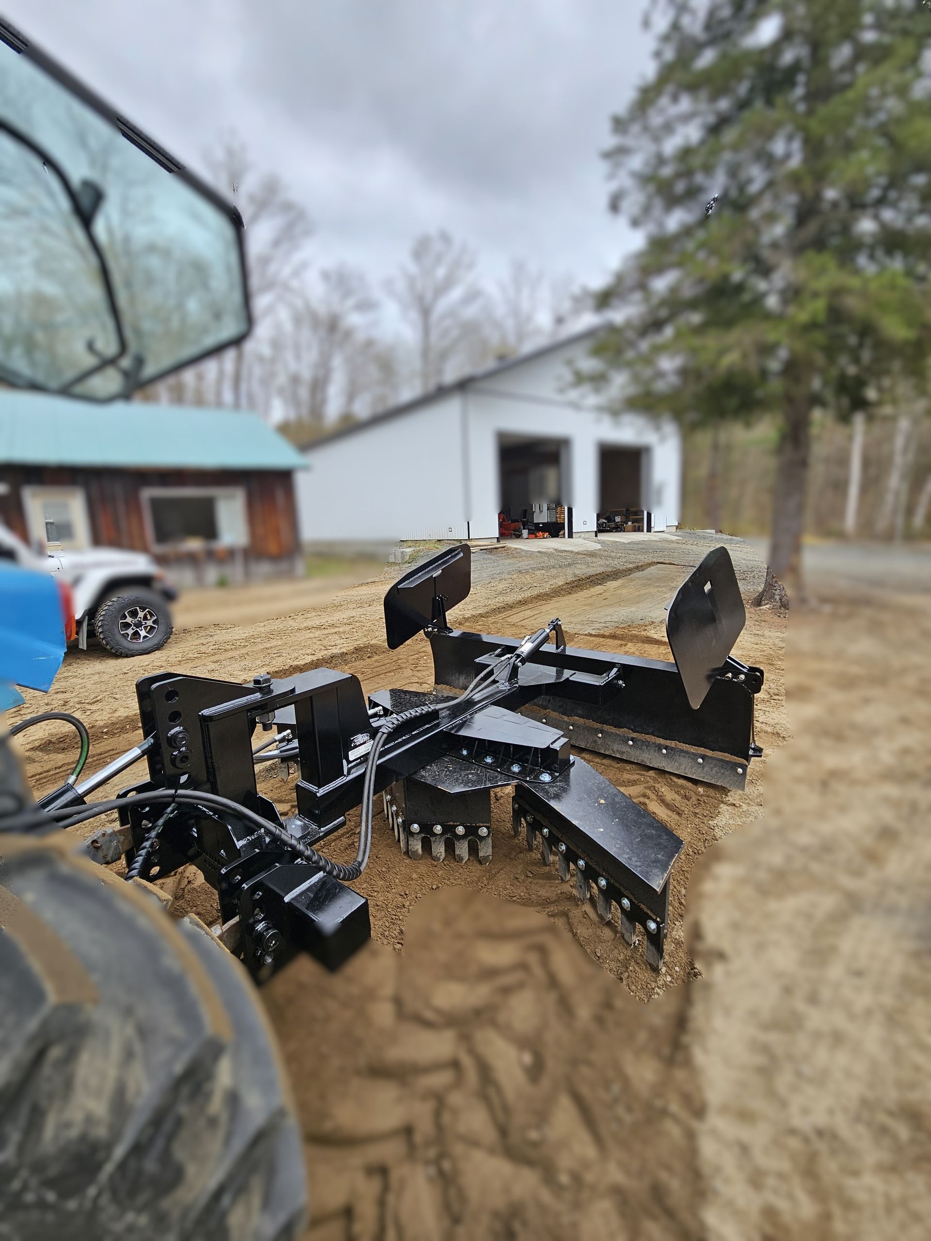 Un tracteur est dans la terre devant une maison.