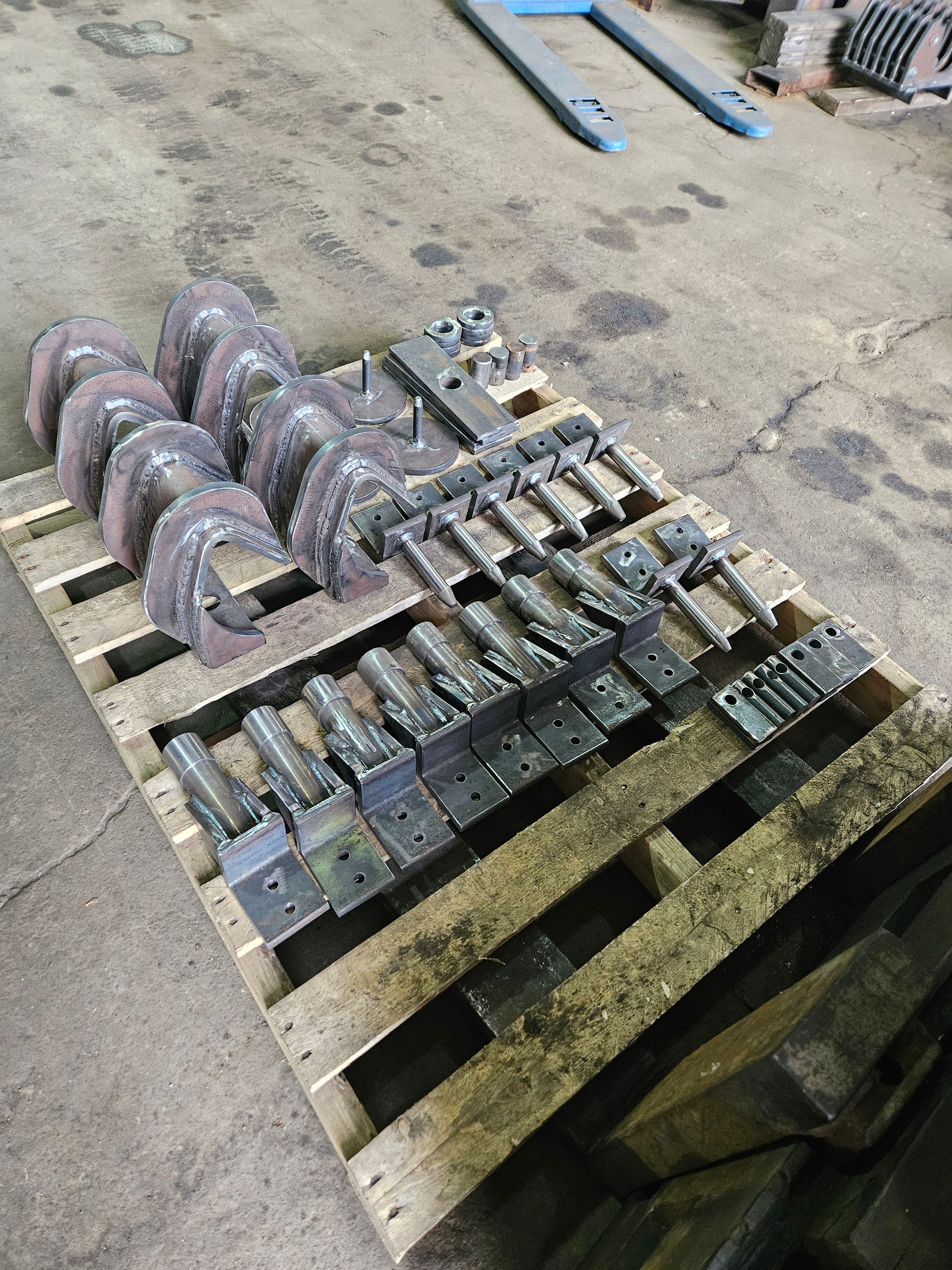 Une palette en bois avec un tas de pièces métalliques dessus.