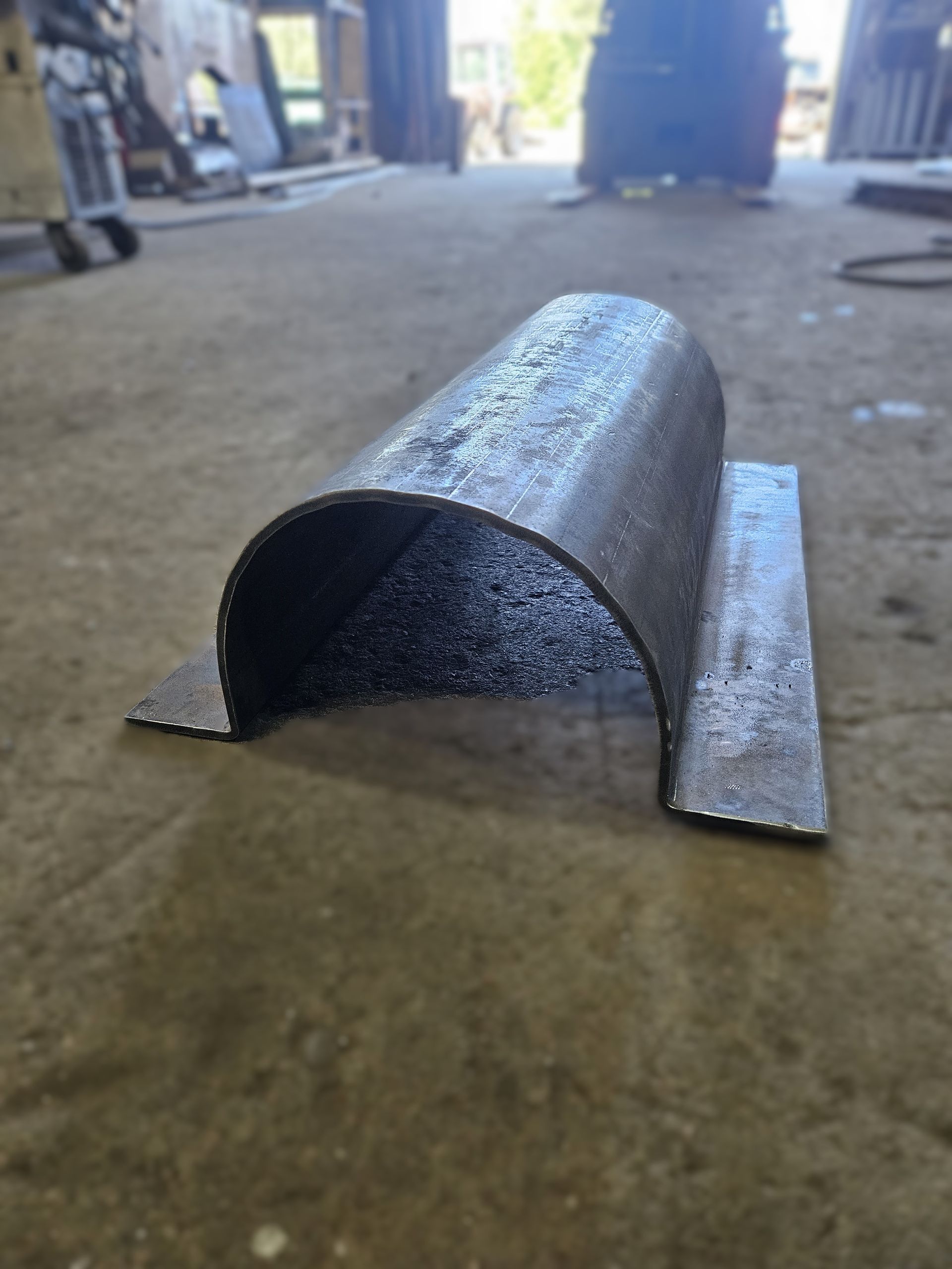 Un tuyau métallique est posé sur le sol dans un garage.