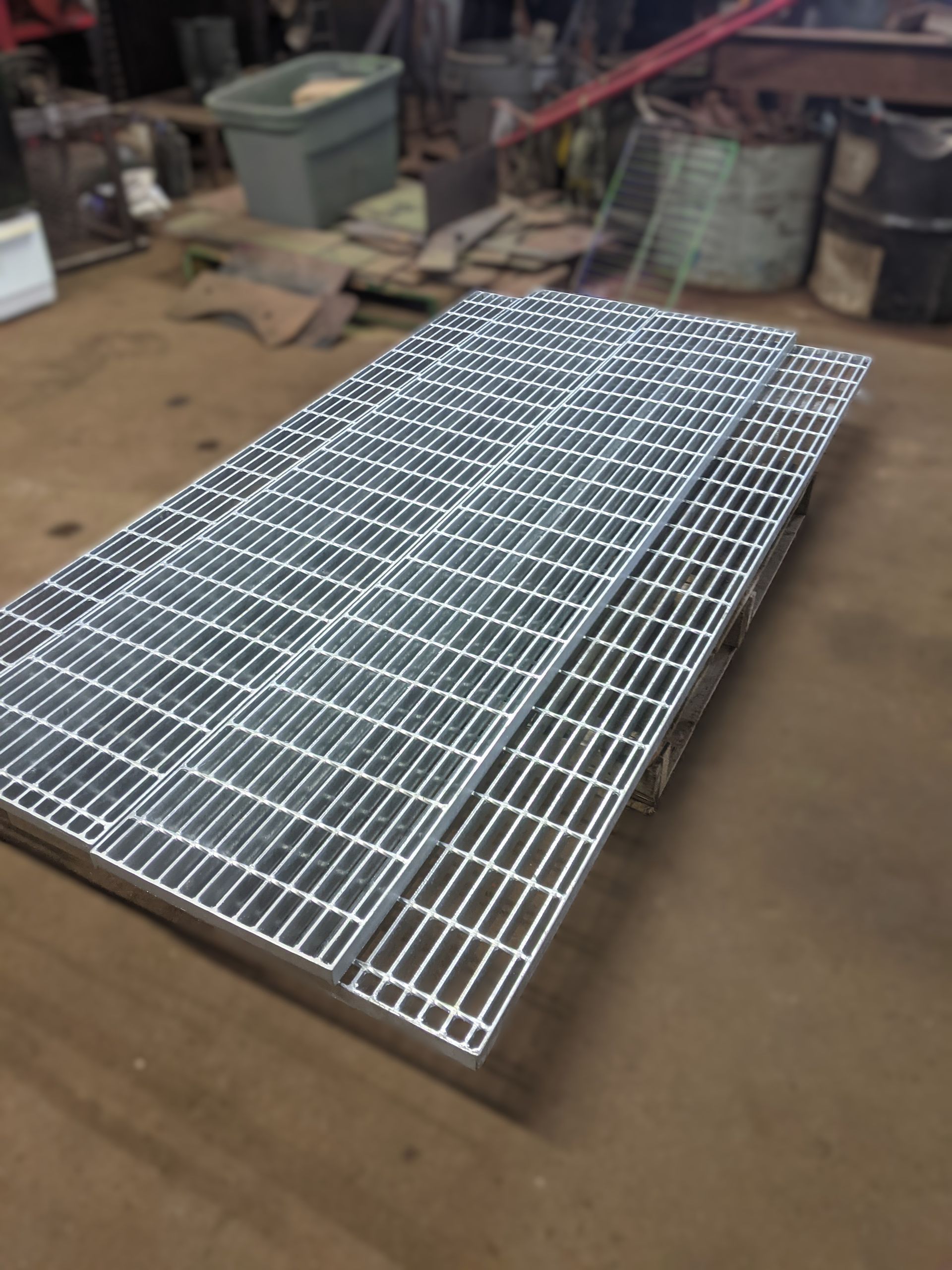 Une grille métallique est posée sur un sol en terre battue.