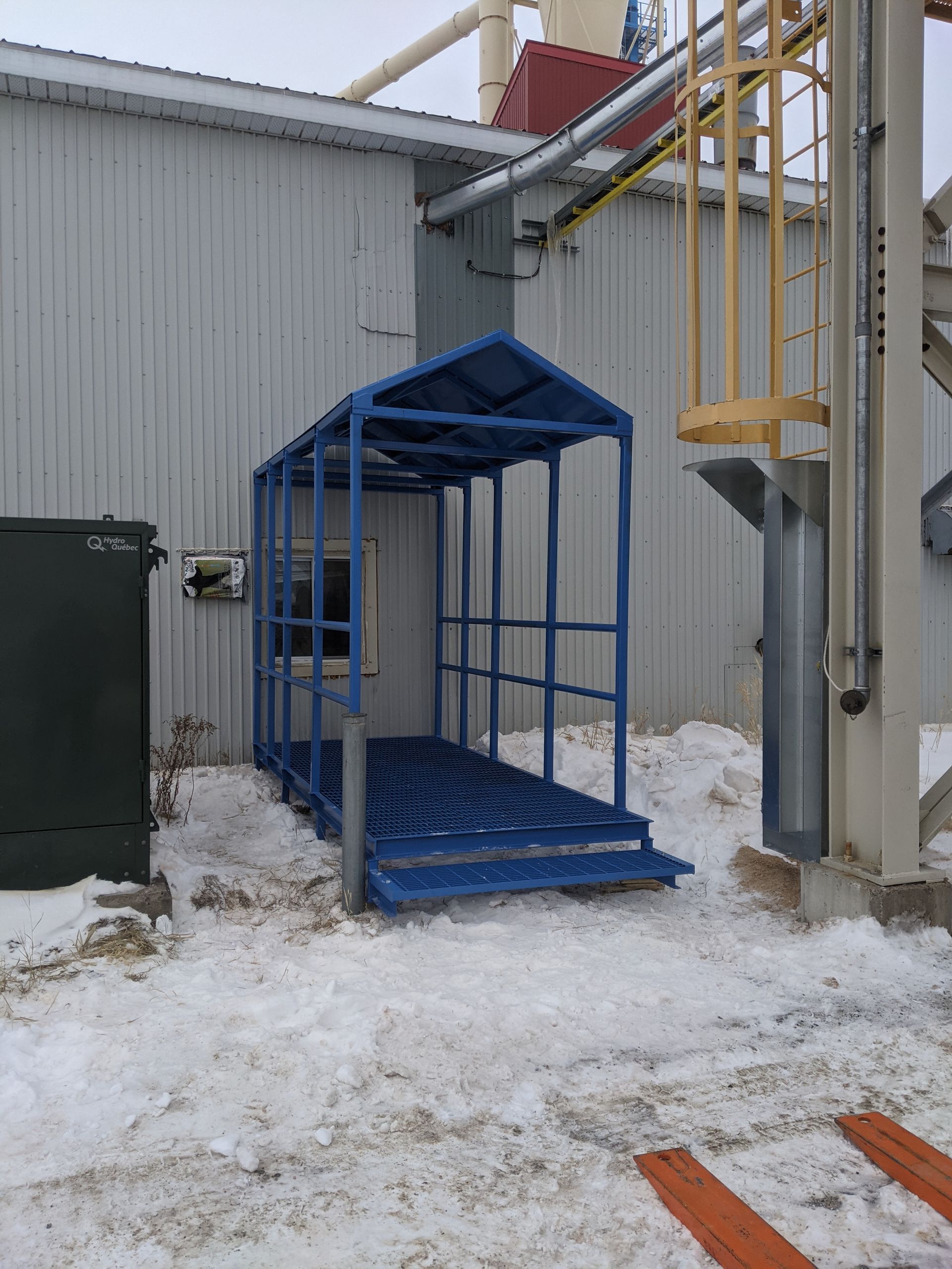 Une structure bleue est assise dans la neige devant un bâtiment