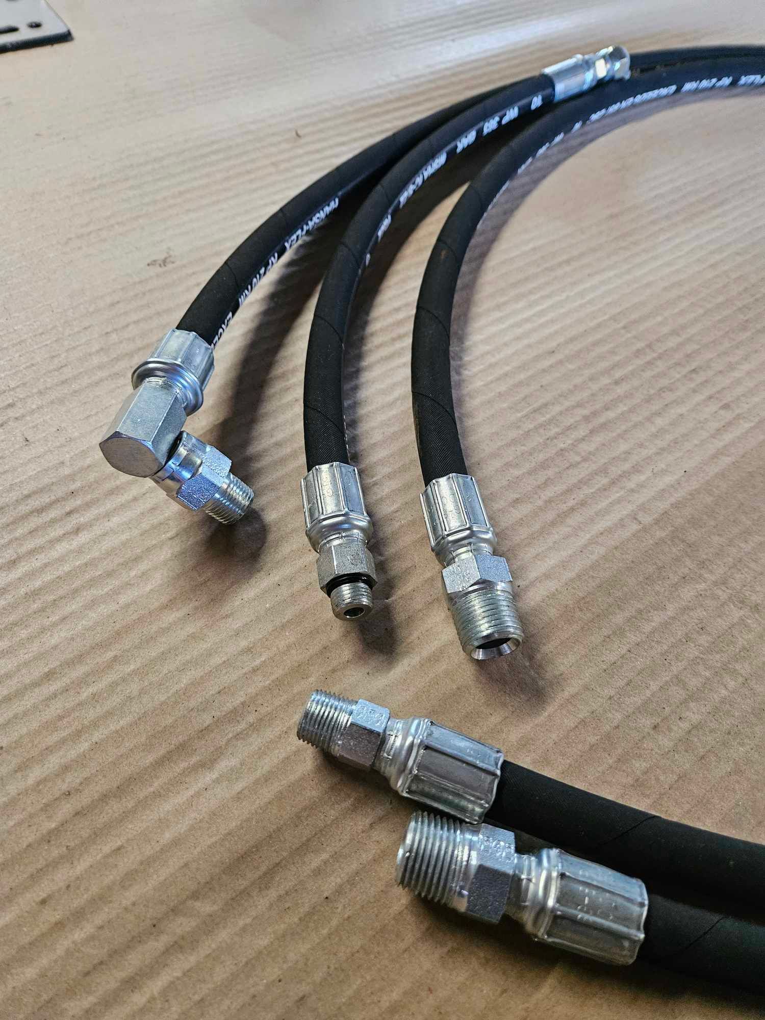 Trois tuyaux hydrauliques sont posés sur une table en bois.