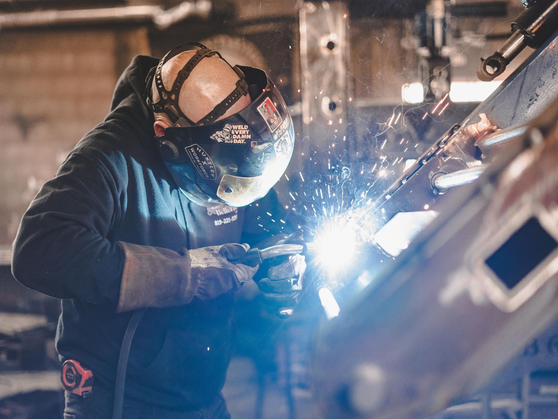 Un homme soude un morceau de métal dans une usine.