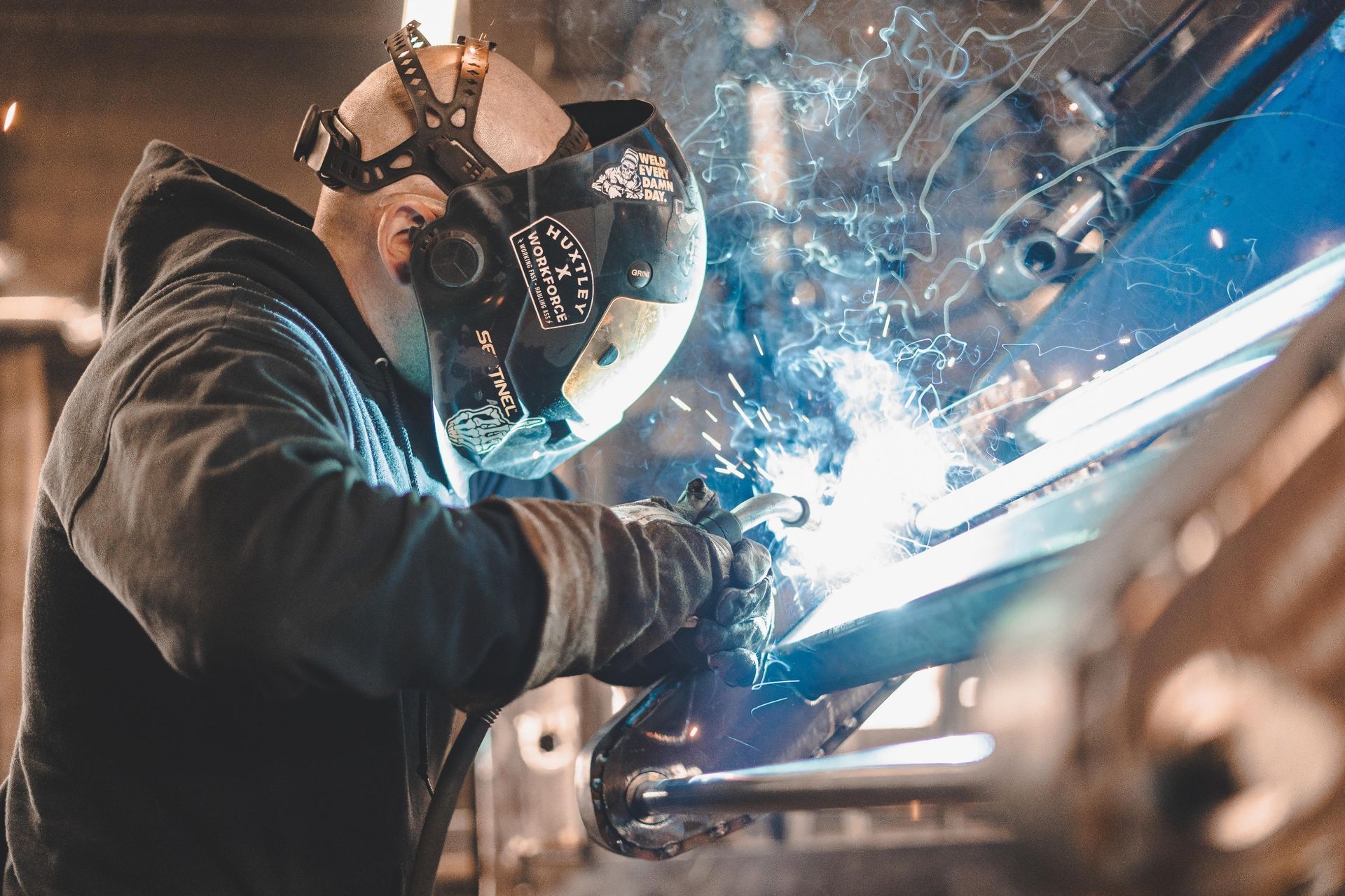 Un homme portant un masque de soudage soude un morceau de métal.