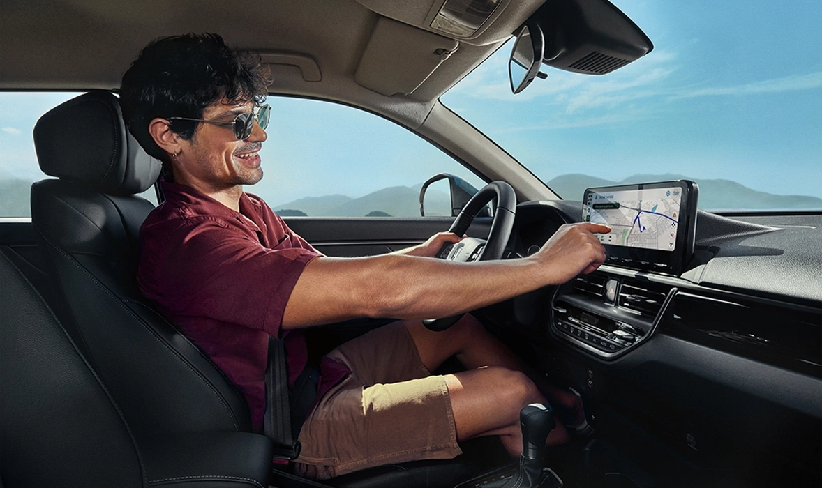 Mulher sorrindo enquanto dirige um carro, com as mãos no volante e a luz do sol brilhando pela janela.