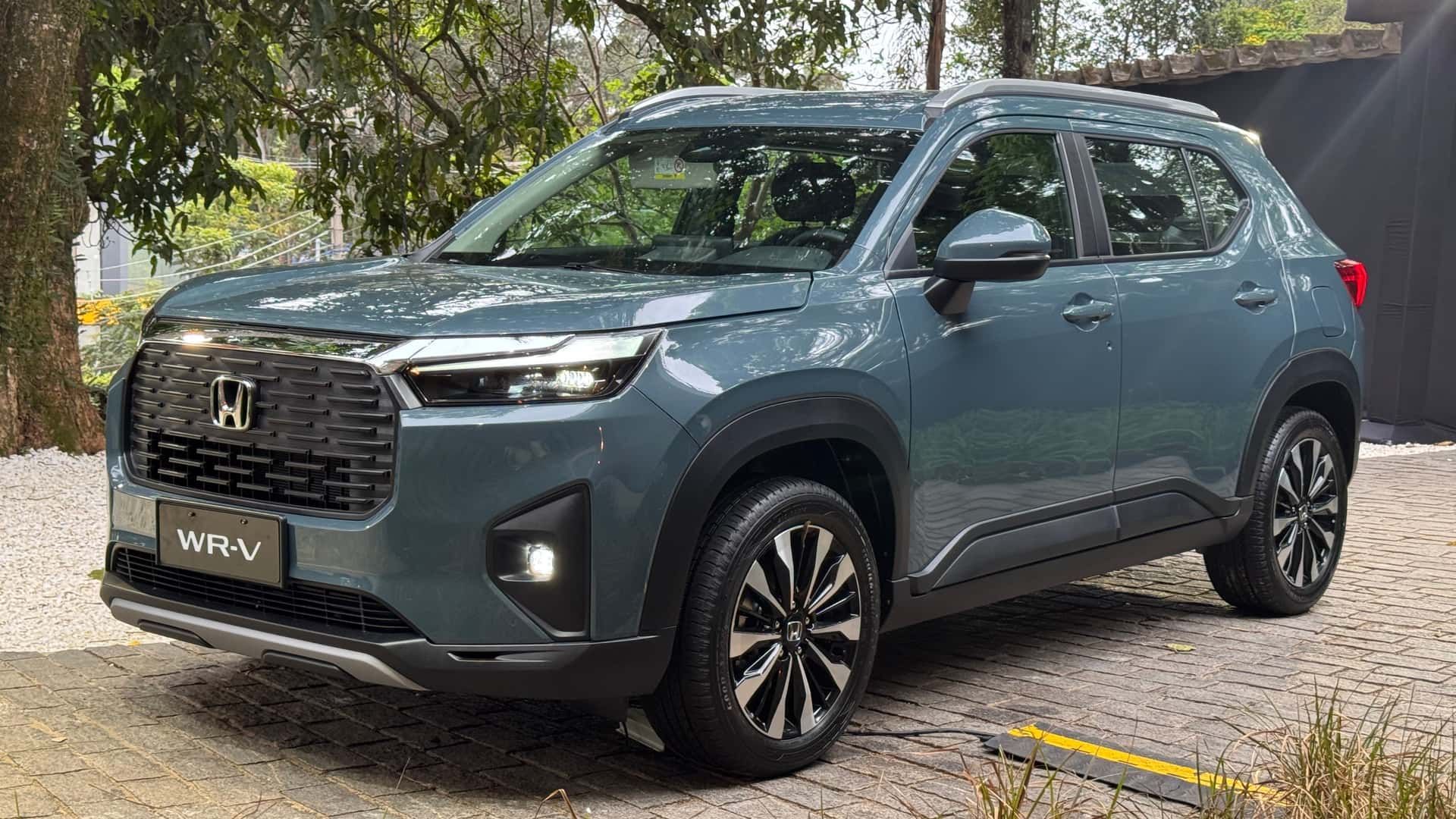 Blue-gray Honda SUV parked outdoors on a tree-lined street, front-left view.