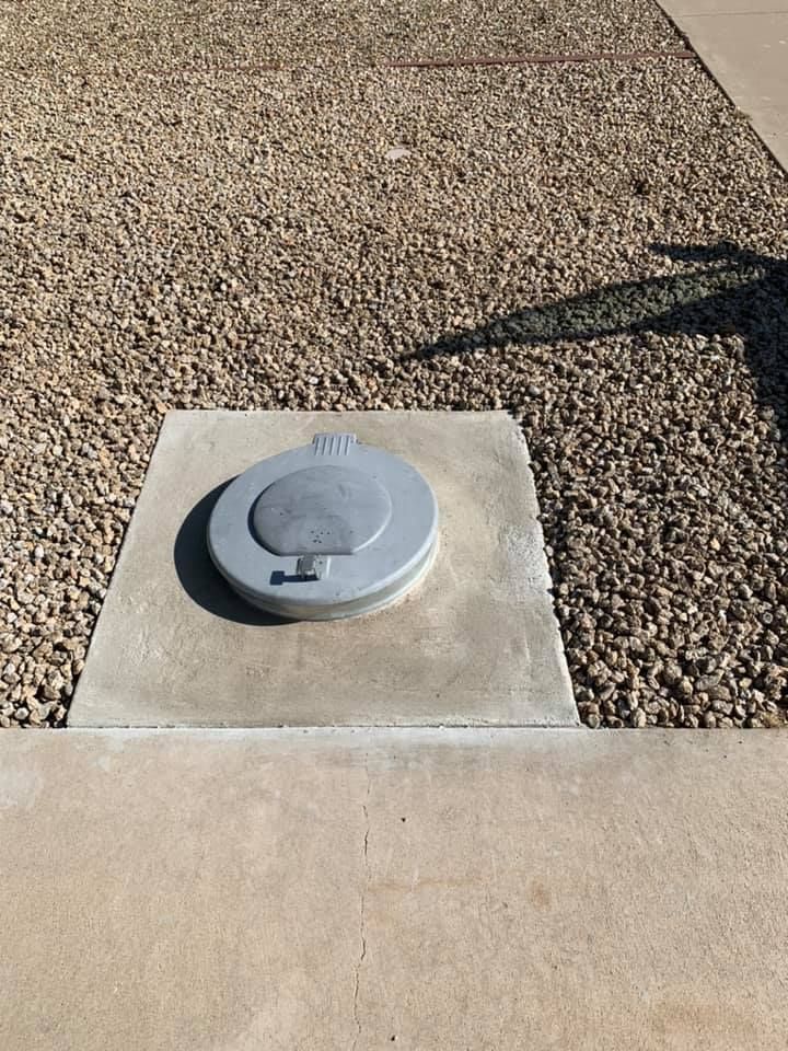 Concrete pad with gravel, circular gray lid marked 