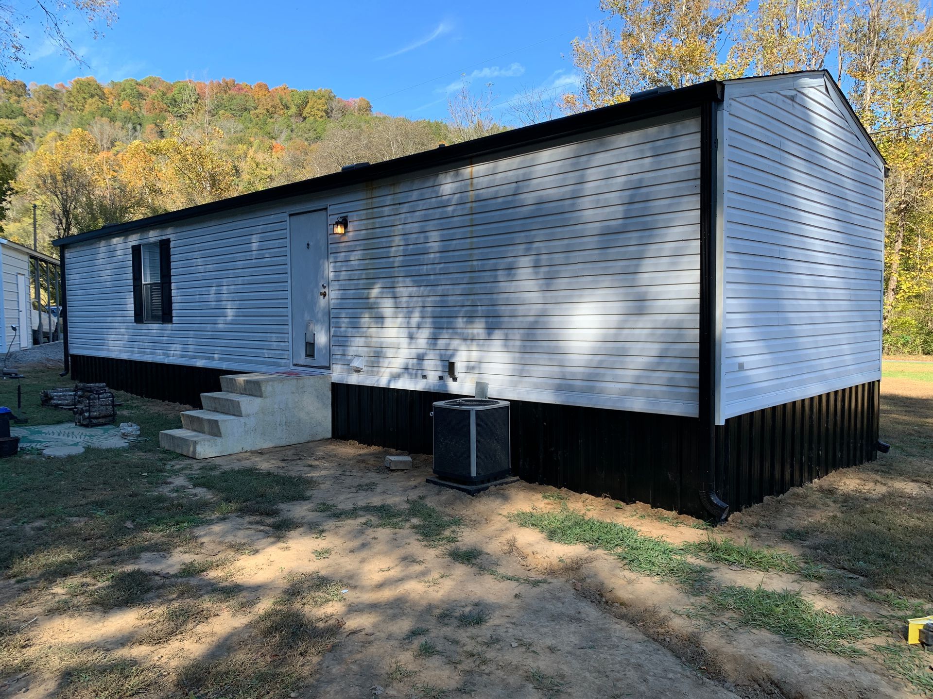 Mobile home with white siding, black trim, and steps.