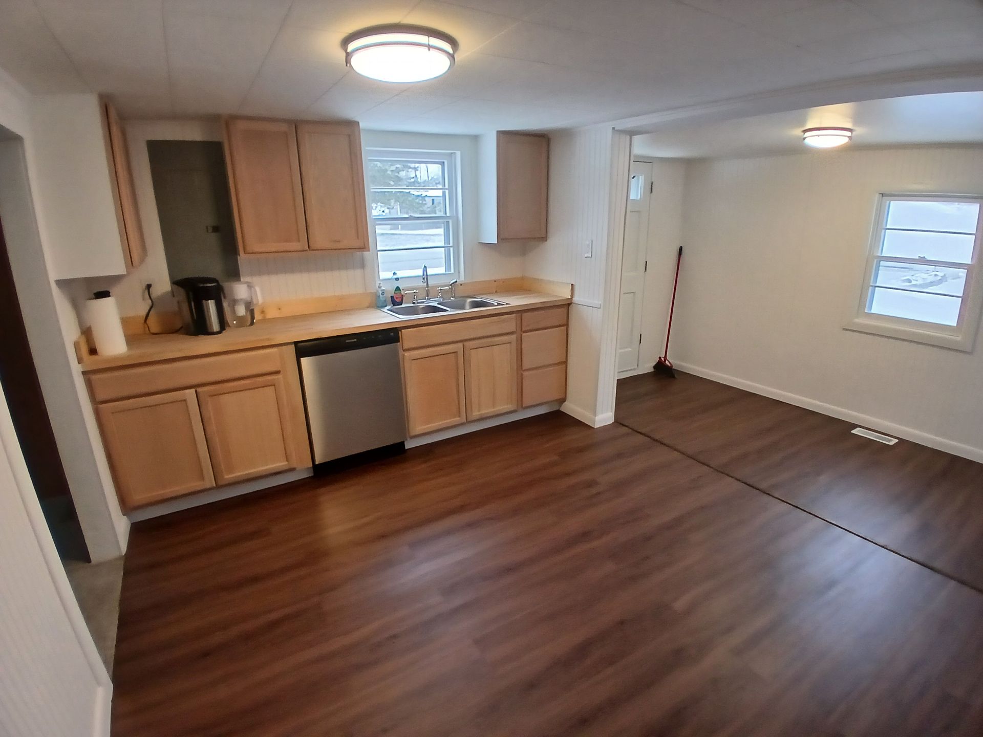 Kitchen with light wood cabinets, stainless steel appliances, and dark wood-look flooring.