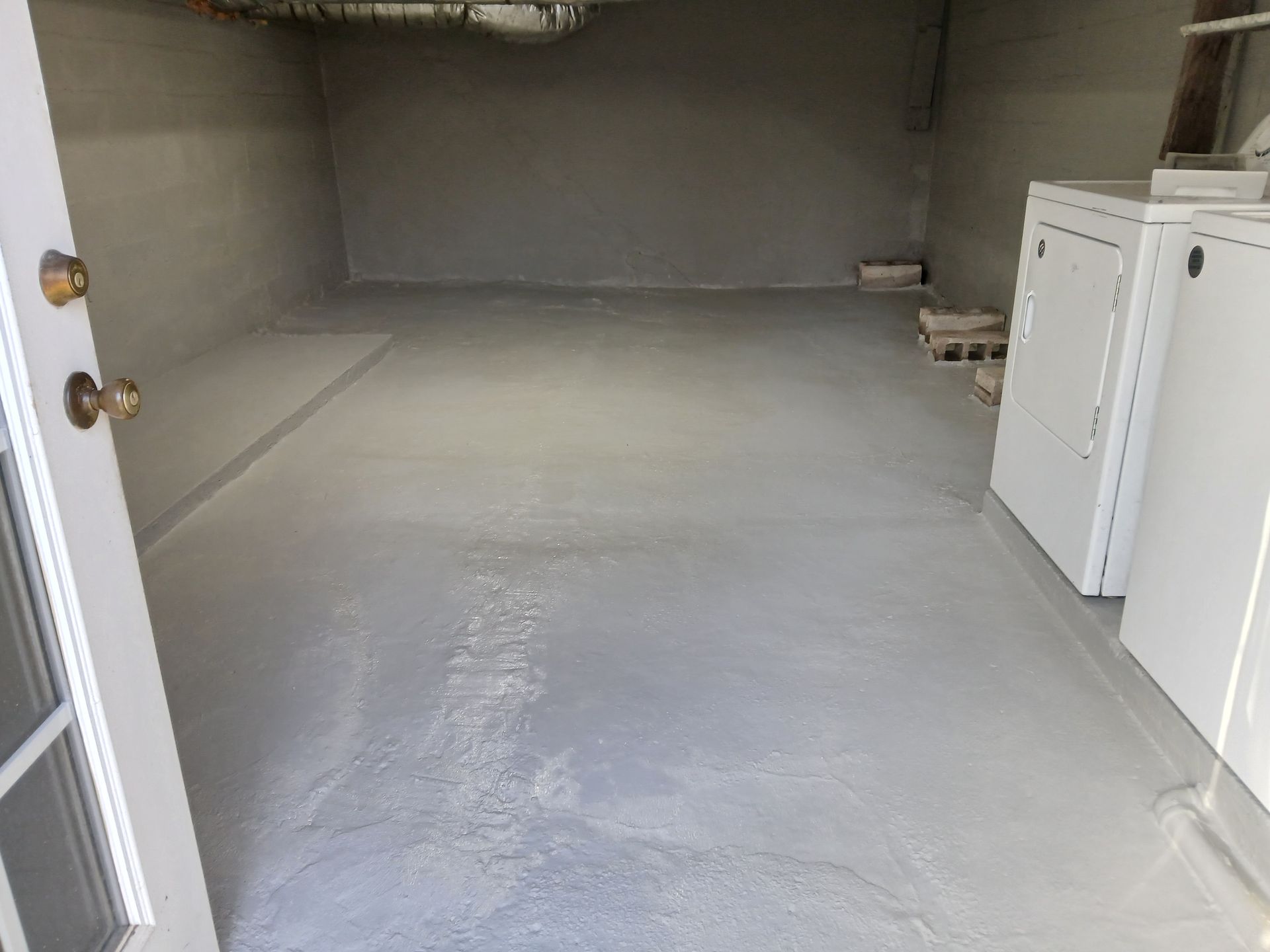 Gray-painted basement room with door open to the left, and washer and dryer on the right.