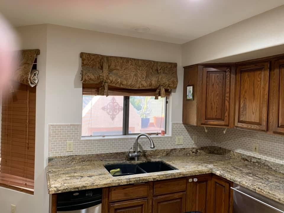 Kitchen with wooden cabinets, granite countertops, and a window with a patterned shade.
