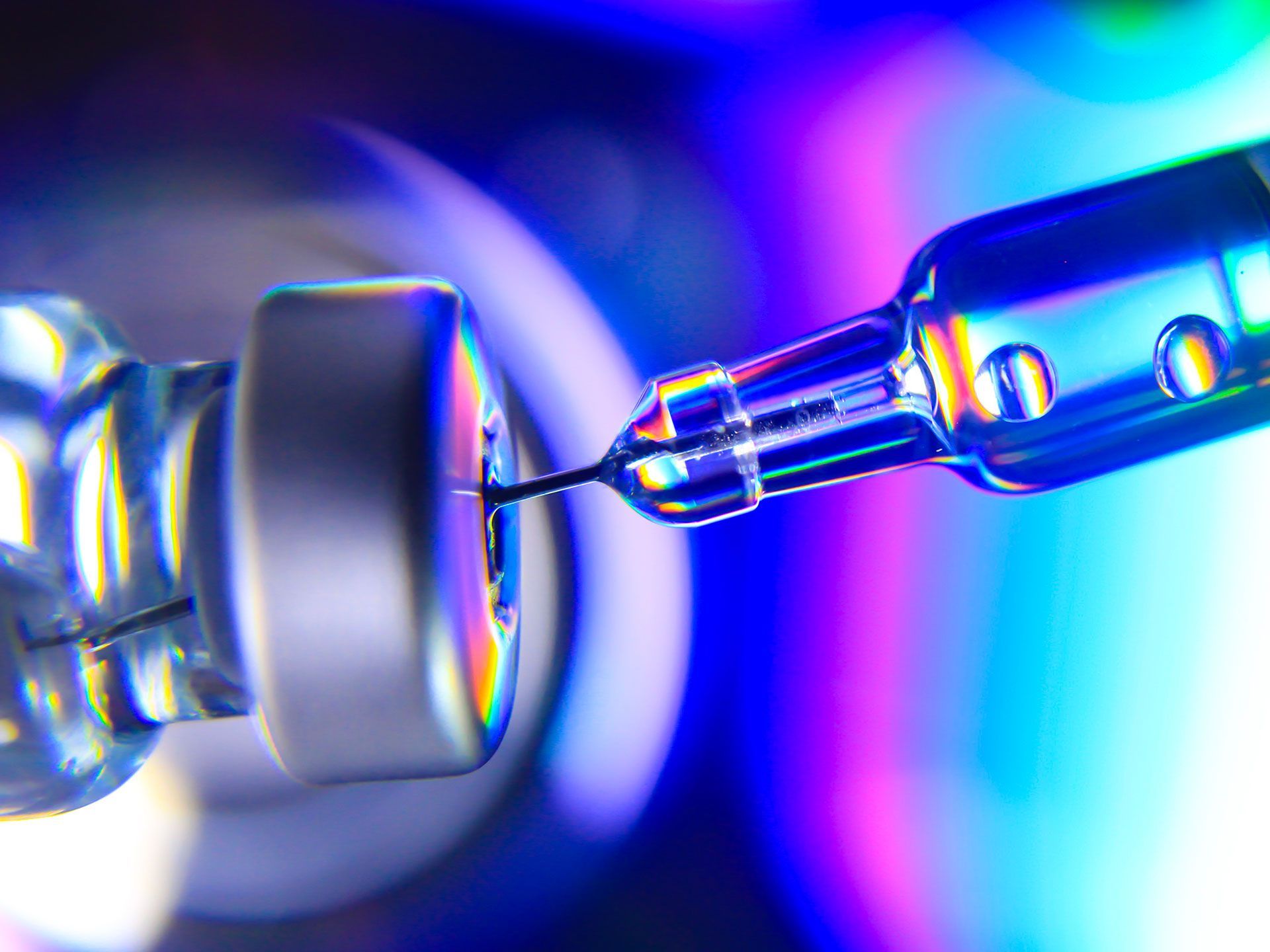 Syringe injecting liquid from a vaccine vial, colorful, macro.