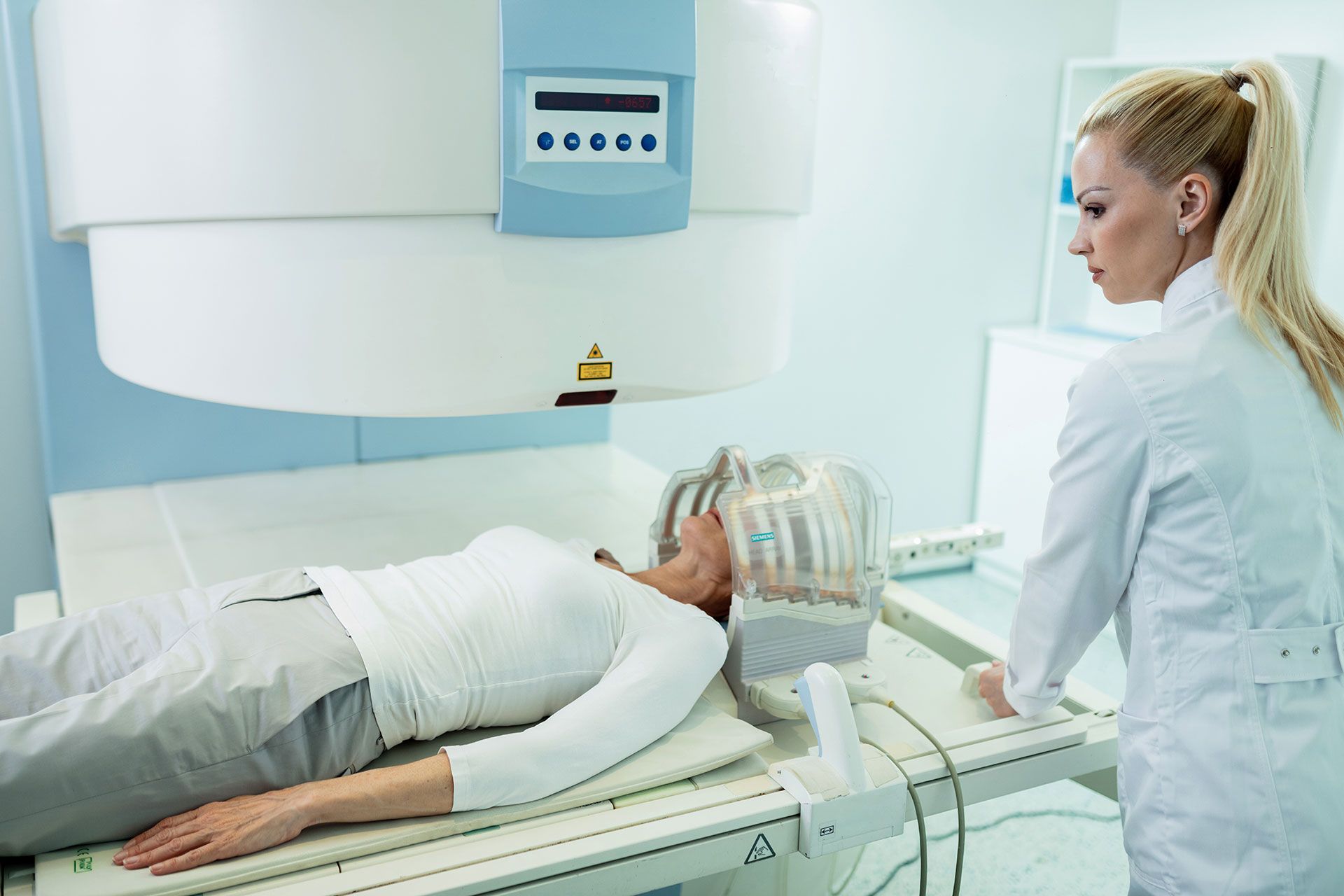 Woman in medical scanner, doctor beside.