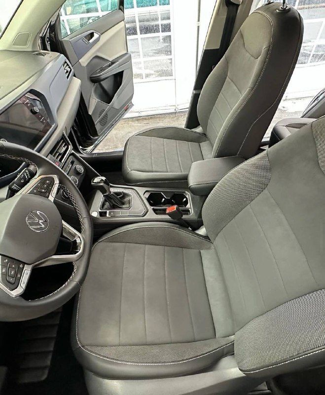 The interior of a car with gray seats and a steering wheel.