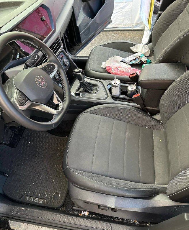 The inside of a car with a steering wheel and seats.