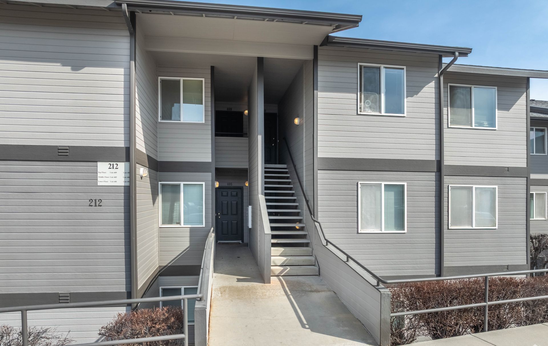 A gray apartment building with stairs leading up to the second floor.