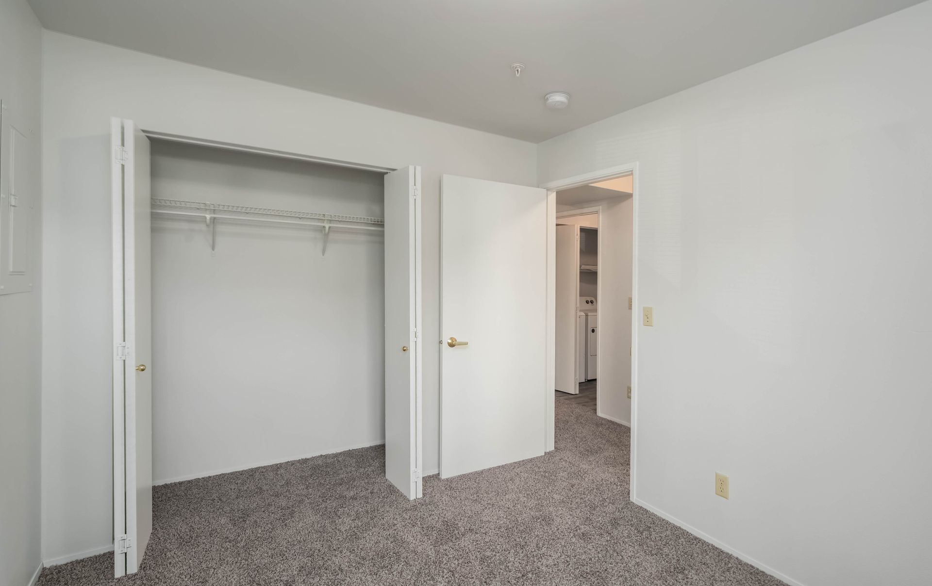 An empty bedroom with two closets and a carpeted floor.