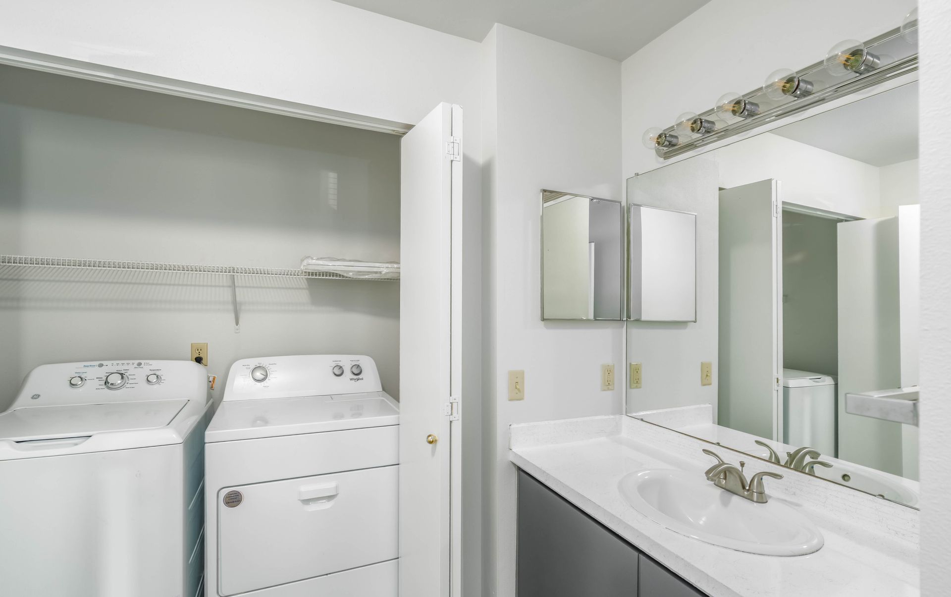 A bathroom with a washer and dryer and a sink.