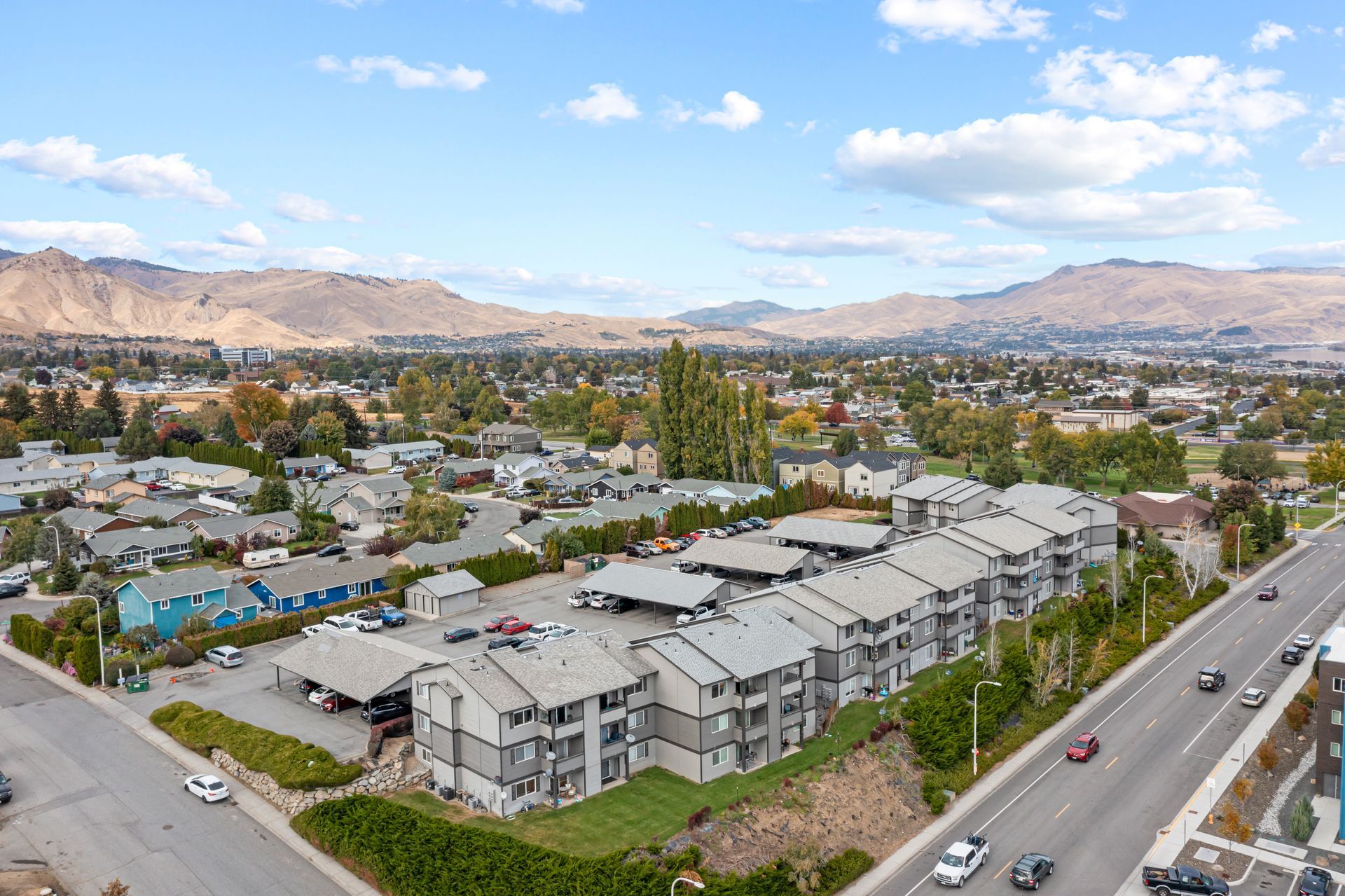 An aerial view of a residential area with a highway and mountains in the background.
