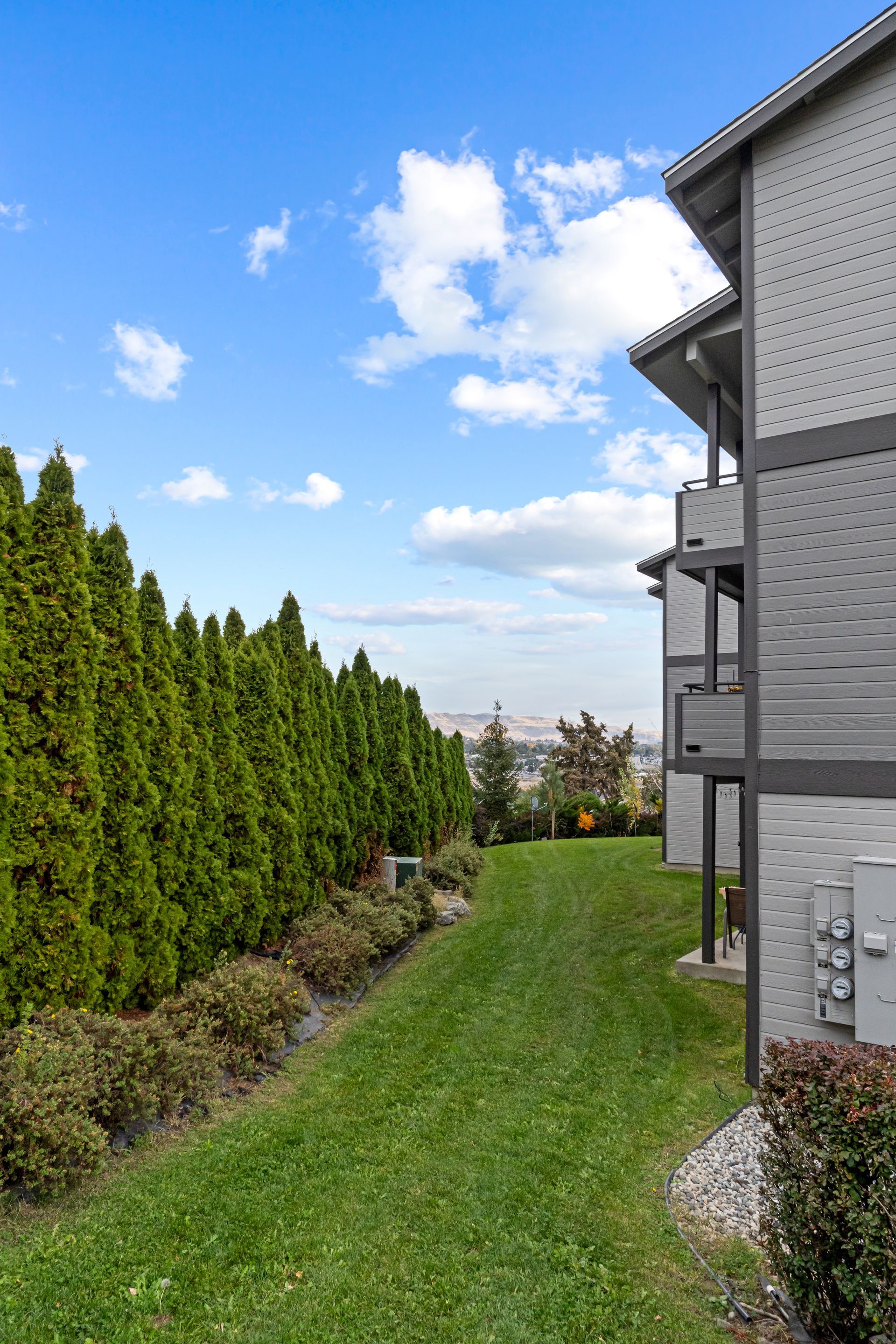 A lush green lawn between two apartment buildings with a blue sky in the background.