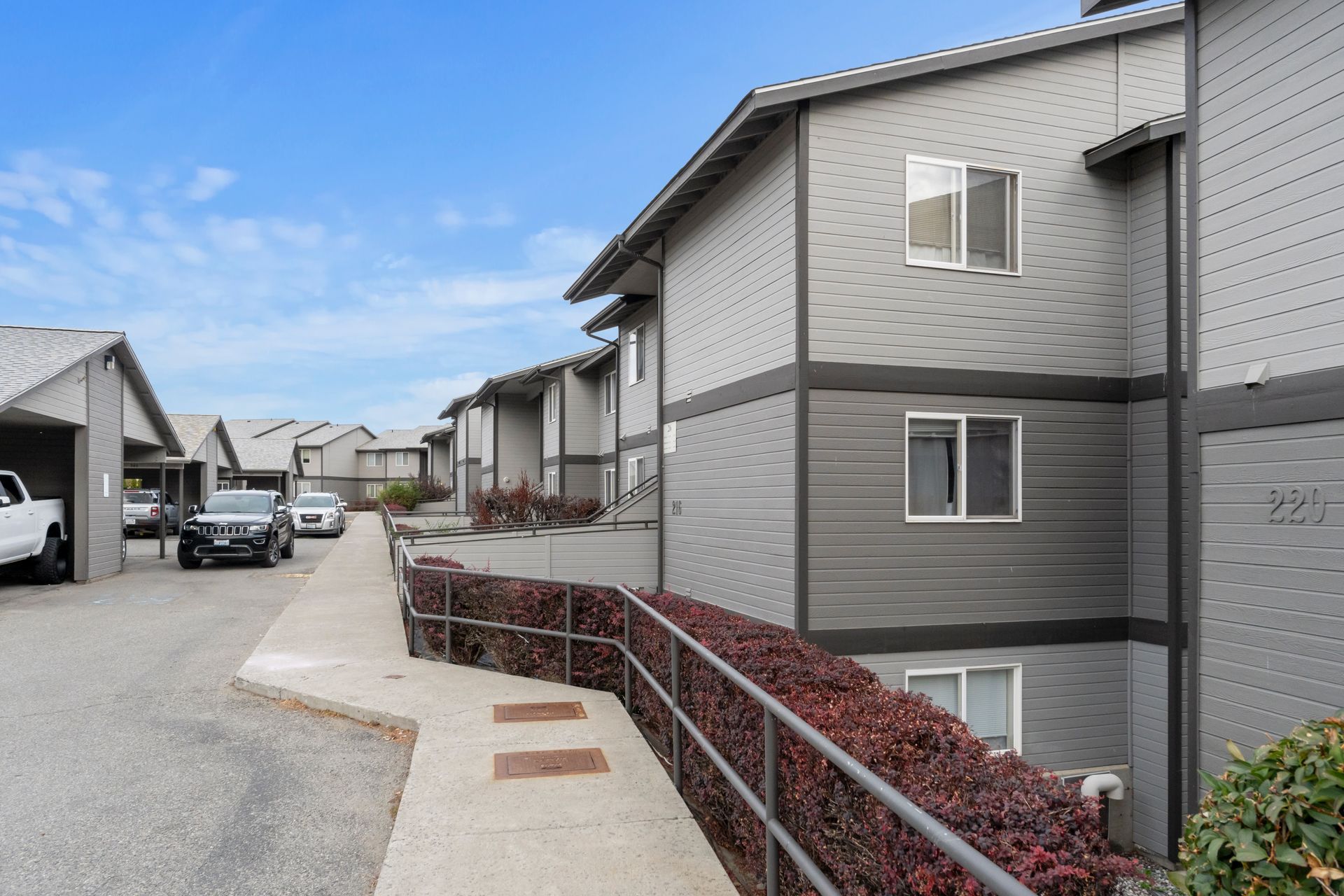 A row of apartment buildings with cars parked in front of them.