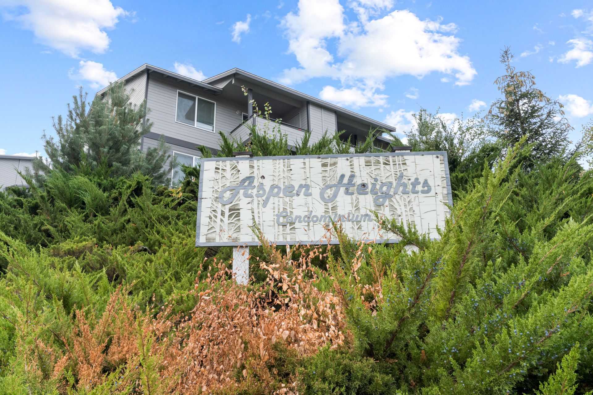 A sign for upper heights is surrounded by bushes and trees