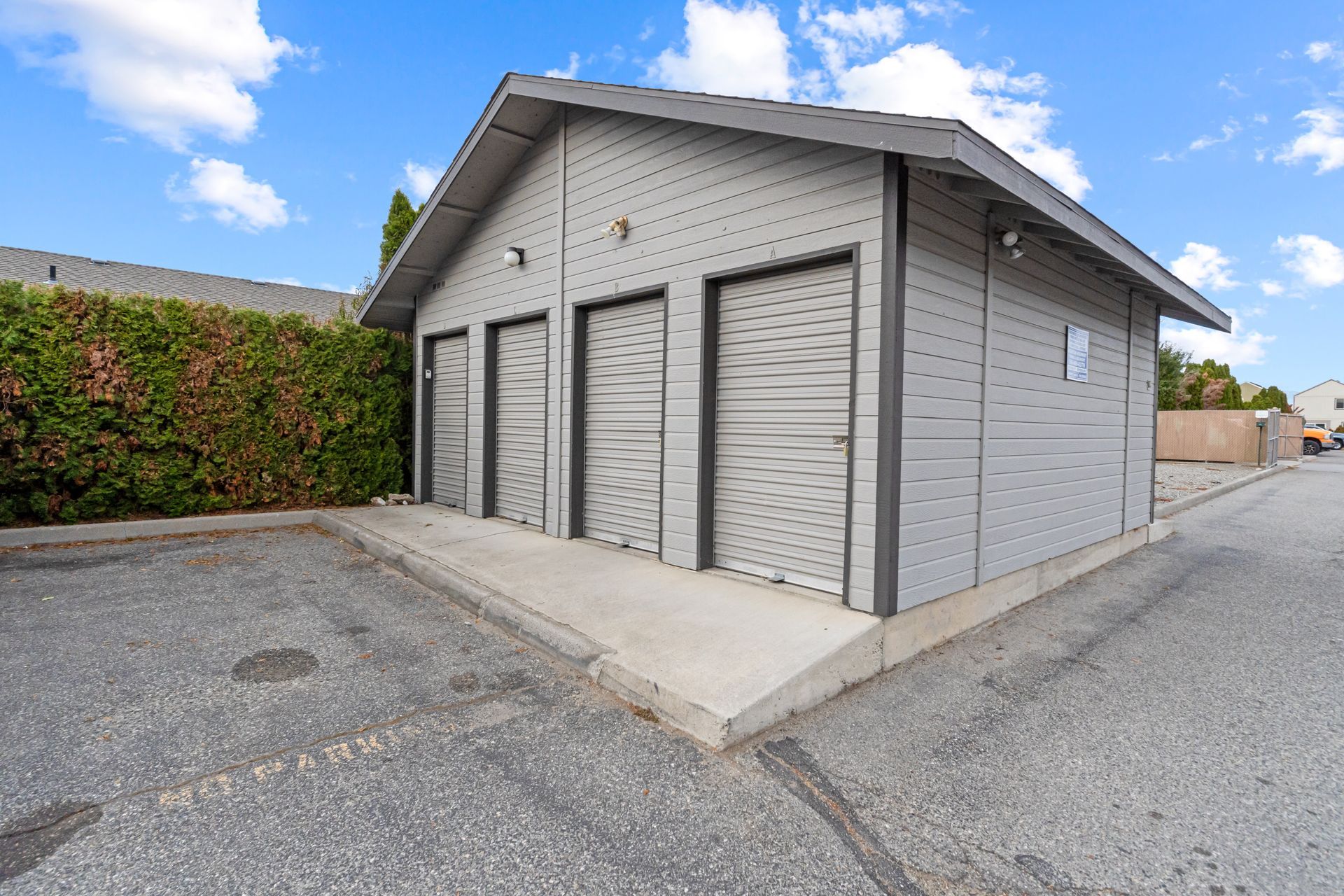 A small building with a lot of doors is sitting on the side of the road.