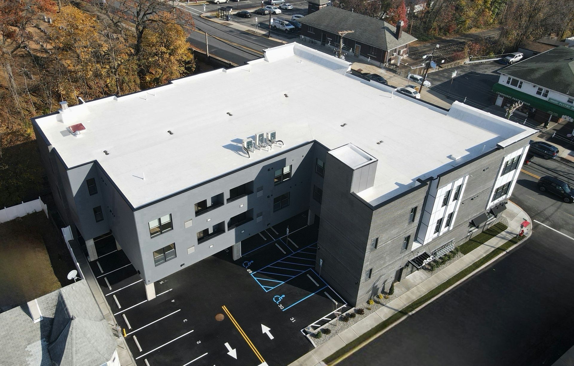 Modern gray commercial building with white roof, parking spaces, and accessible parking signage.