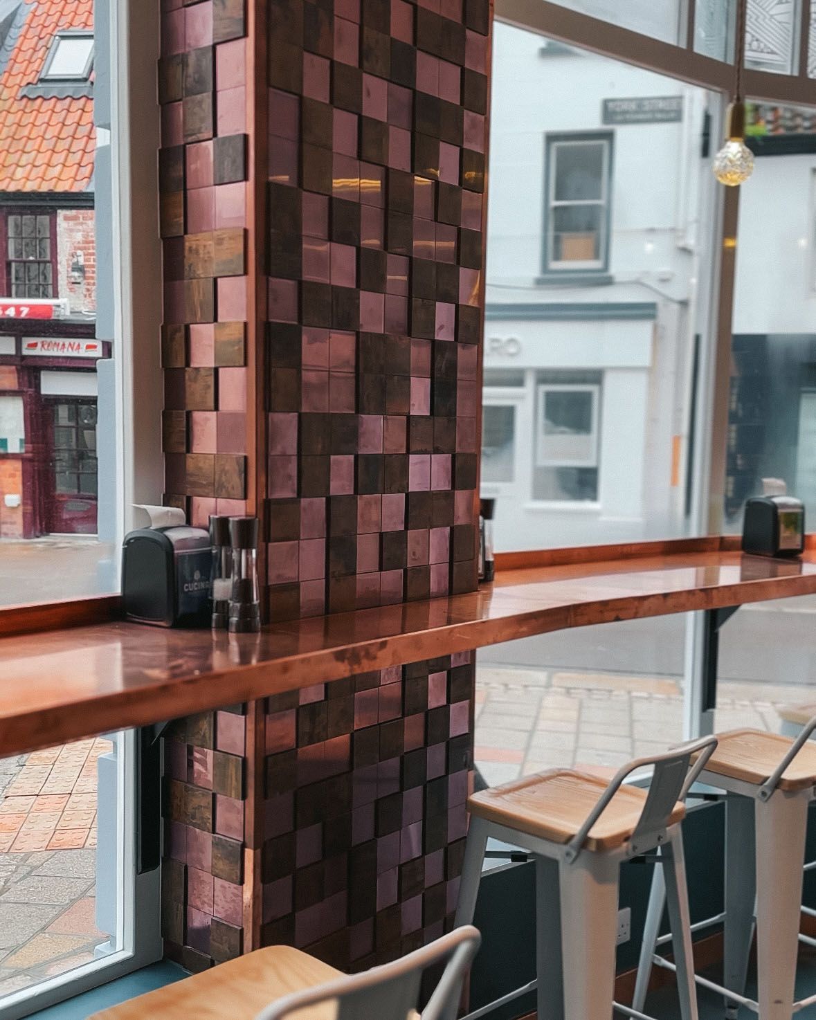 a restaurant with tables and chairs and a copper pillar