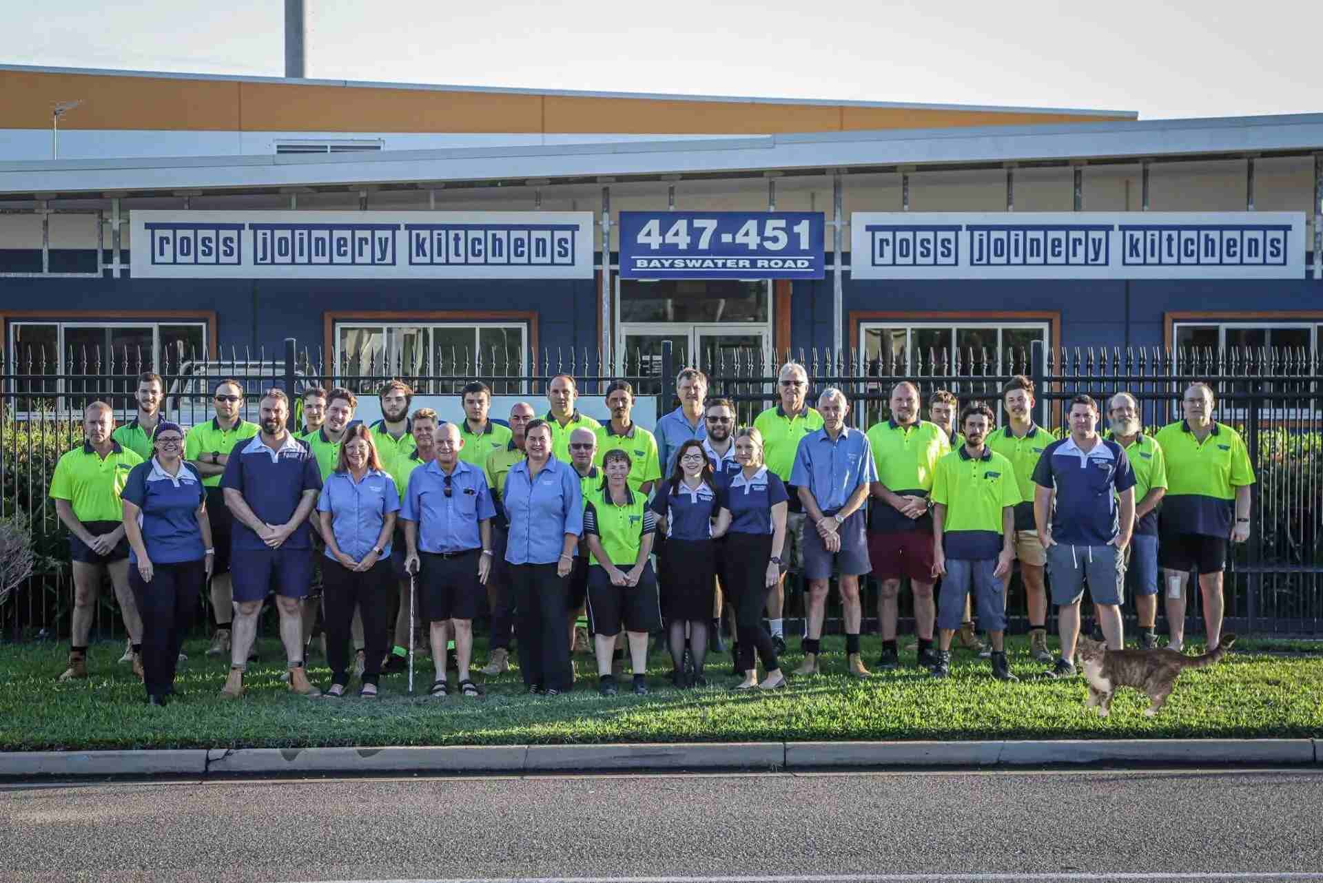A Large Group of People Are Posing for a Picture in Front of a Building — Ross Joinery Kitchens In Garbutt, QLD
