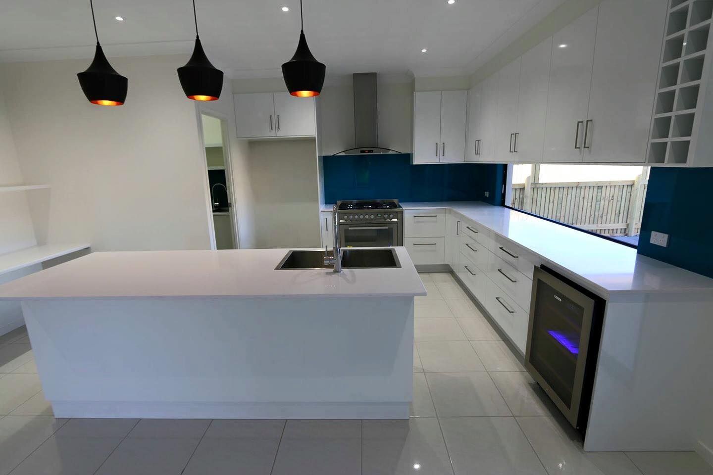 A Kitchen With White Cabinets and a Large Island in the Middle — Ross Joinery Kitchens In Garbutt, QLD