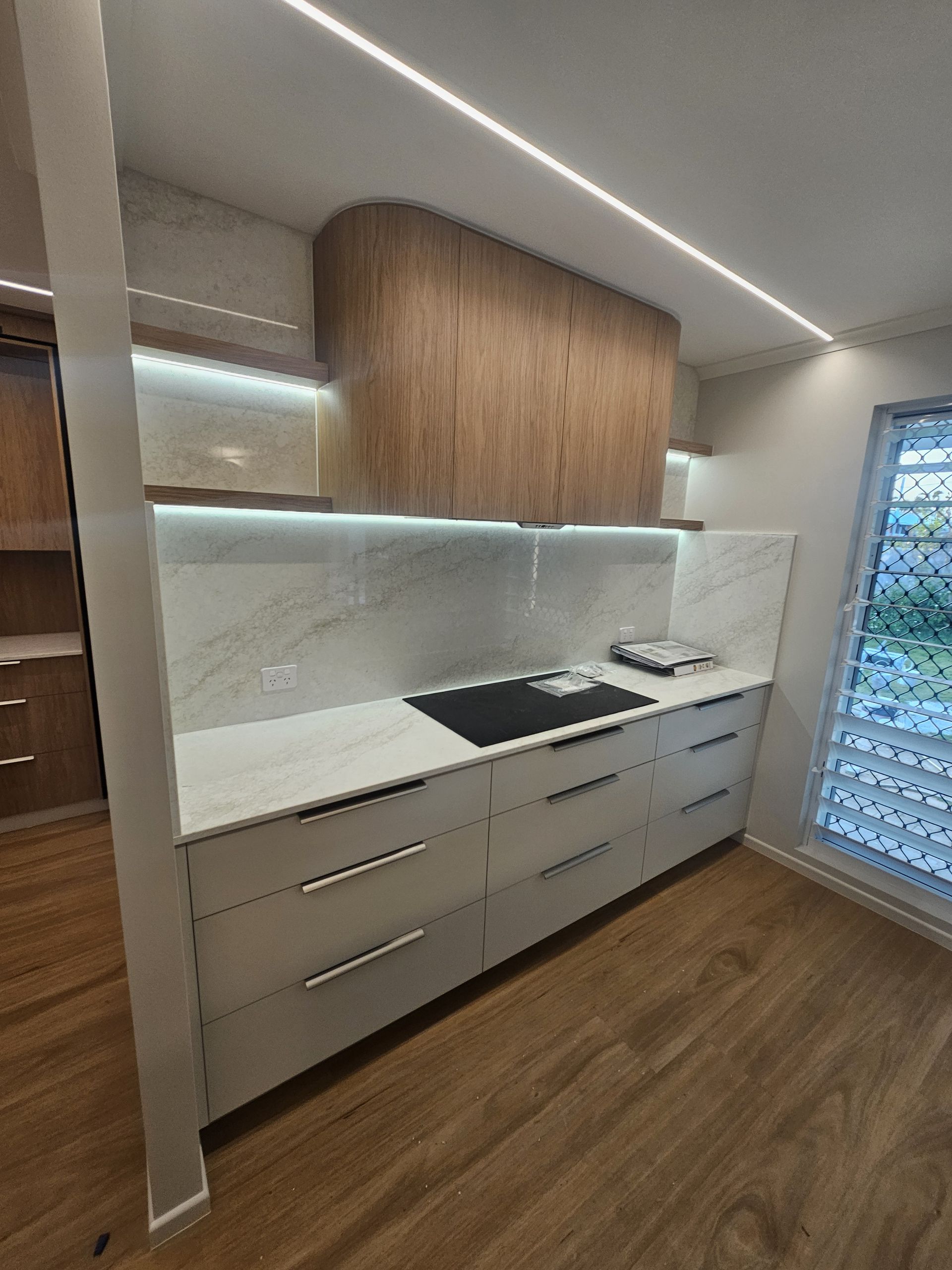 A Curved Desk in a Room With a Wooden Floor — Ross Joinery Kitchens In Garbutt, QLD