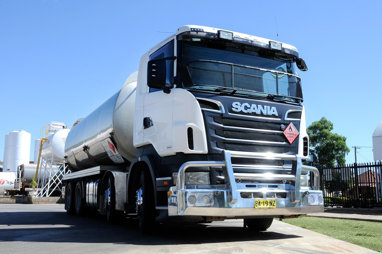 A white scania truck is parked on the side of the road.