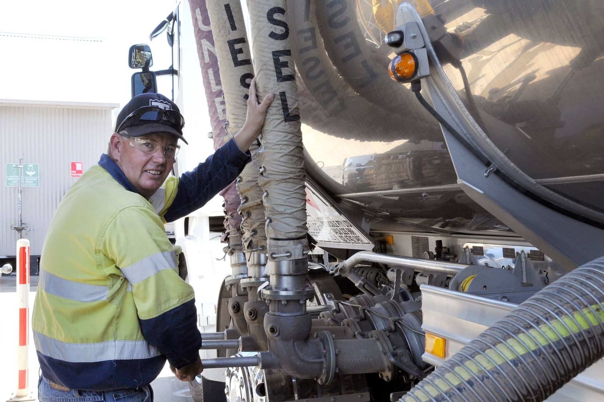 A man in a yellow safety vest is working on a truck