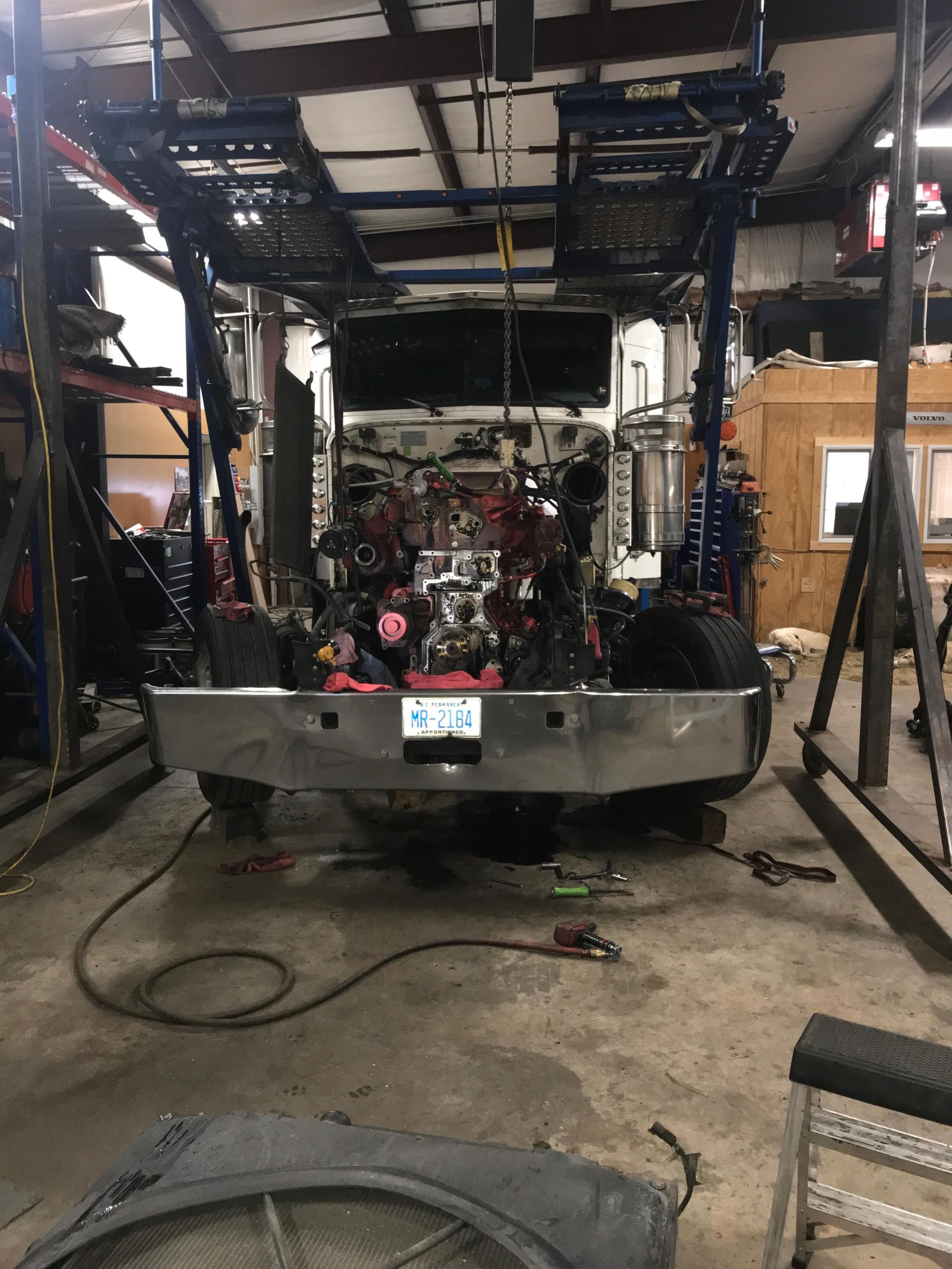 Truck chassis being worked on inside a workshop, with heavy-duty lift.
