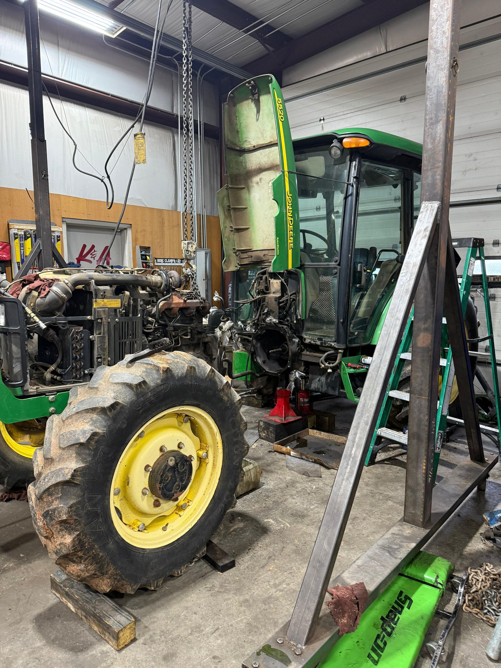 John Deere tractor undergoing repair in a shop.