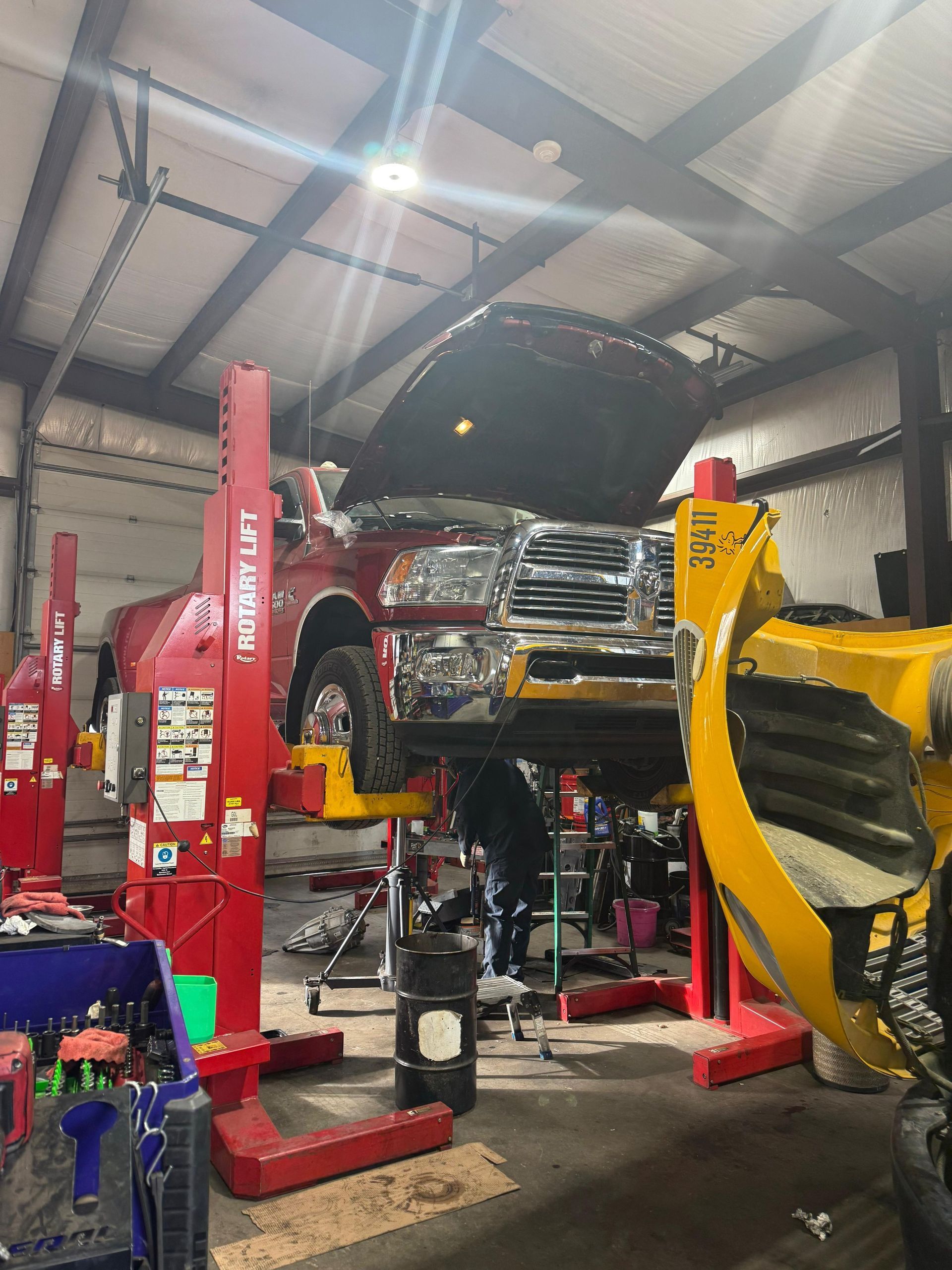 Red truck raised on a lift in a garage with the hood open.