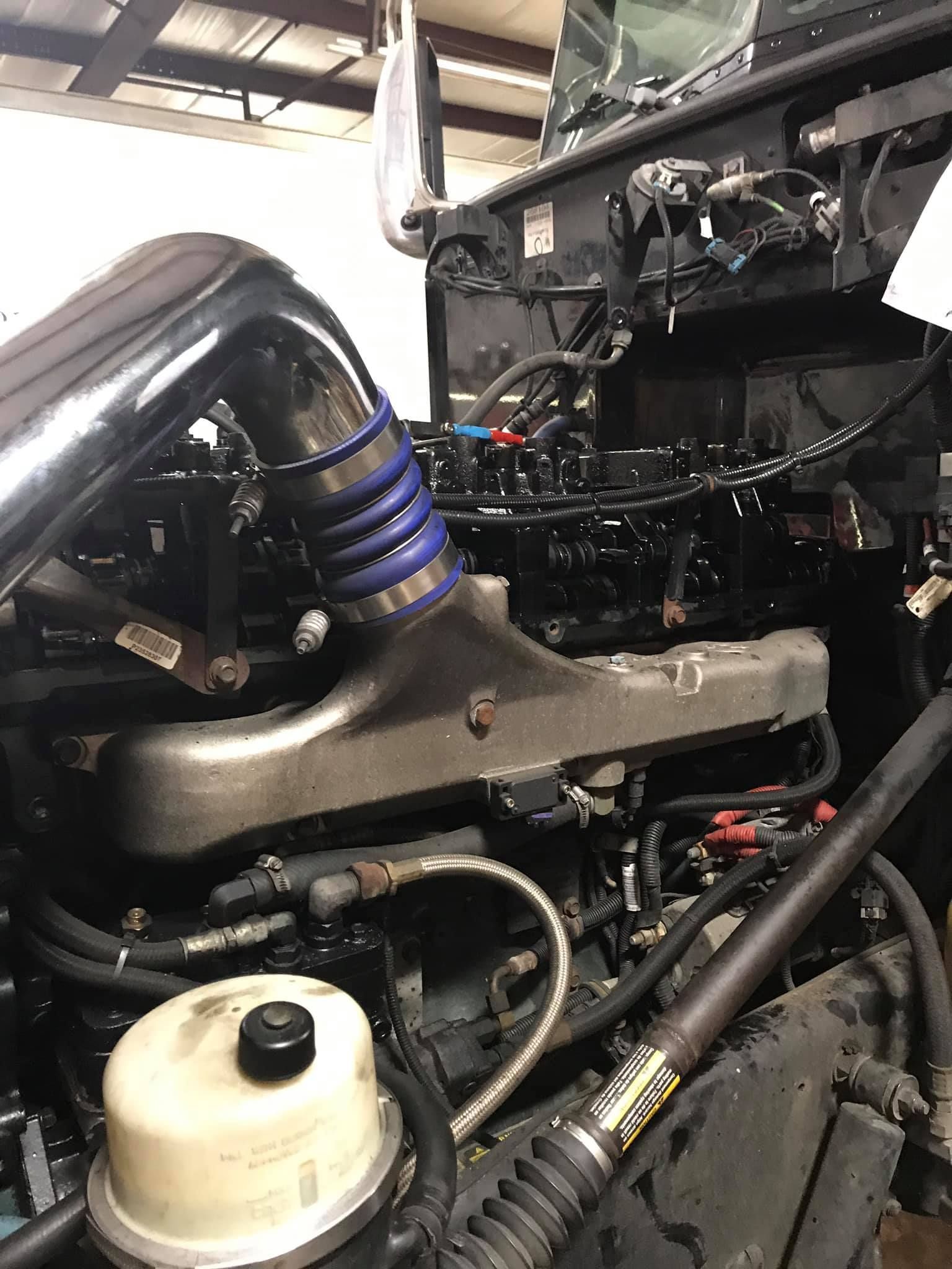 Truck engine with a silver pipe and blue rubber connector.
