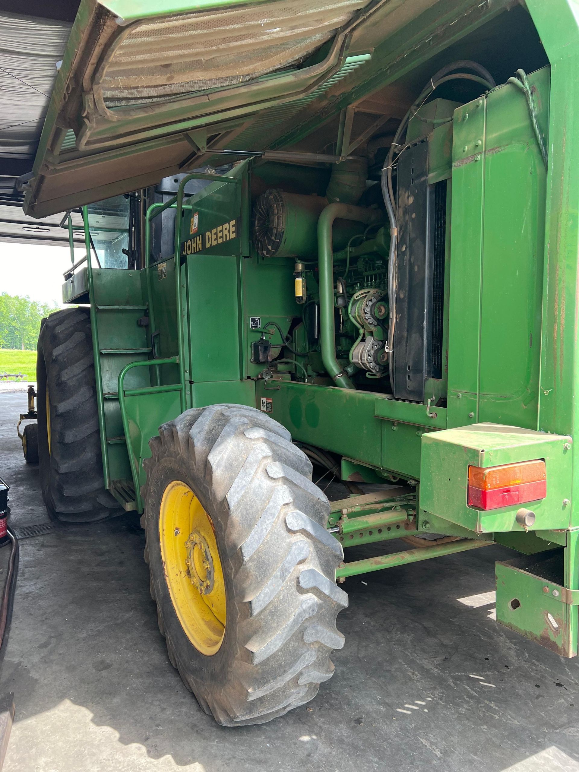Green John Deere combine with large black tires and yellow rims.